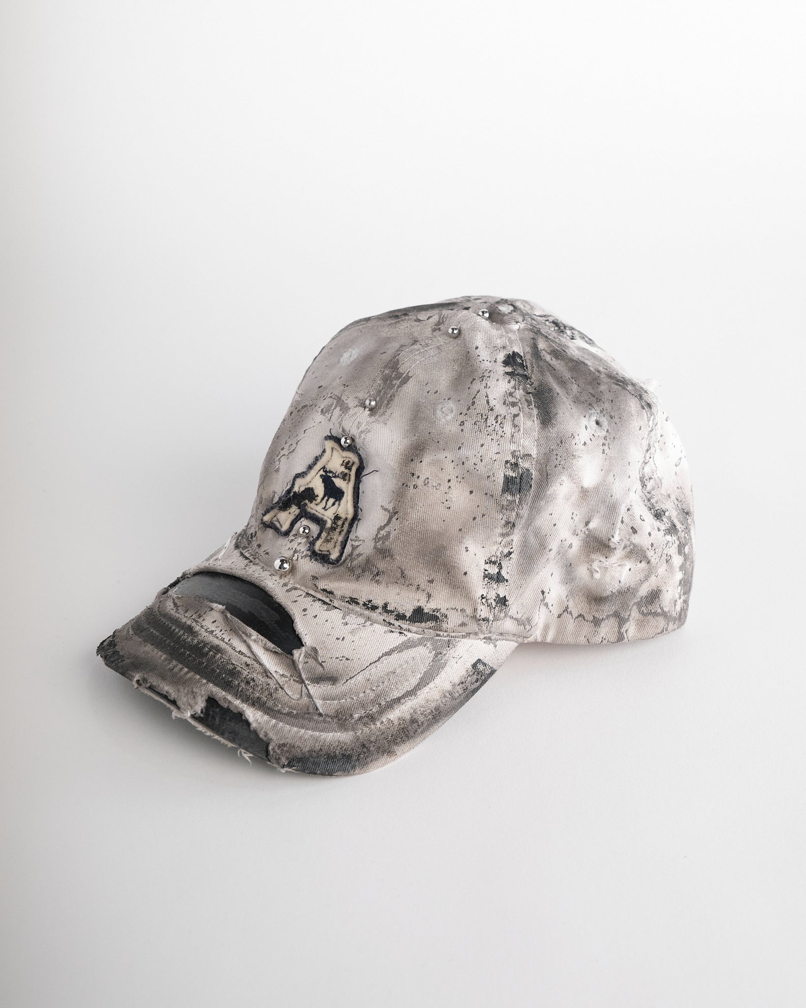Left side of Off-white and black faded ASTROBOI* x Abercrombie hat with custom paint treatment and stainless steel piercing, handmade in NYC.