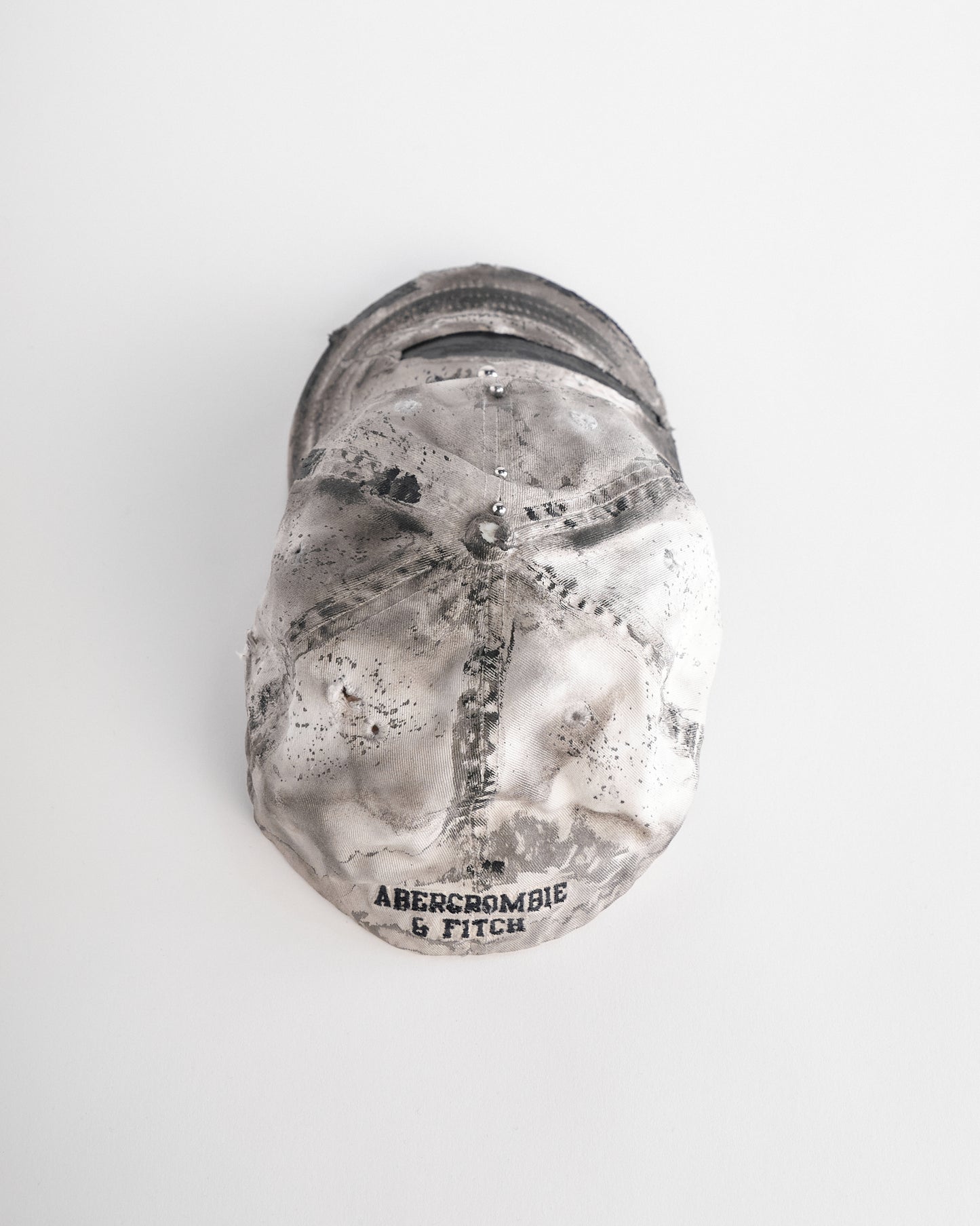 Top of Off-white and black faded ASTROBOI* x Abercrombie hat with custom paint treatment and stainless steel piercing, handmade in NYC.