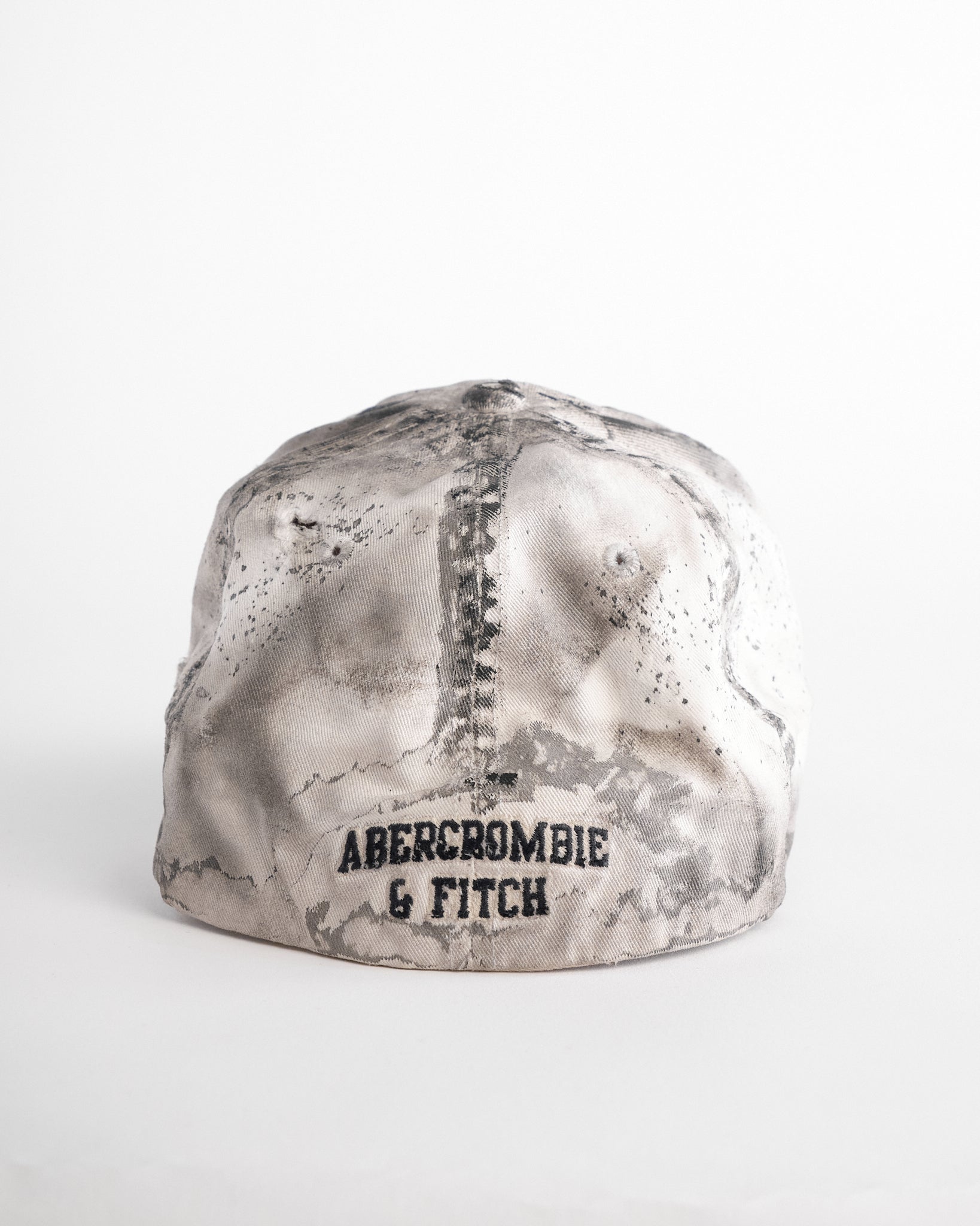 Back side of Off-white and black faded ASTROBOI* x Abercrombie hat with custom paint treatment and stainless steel piercing, handmade in NYC.