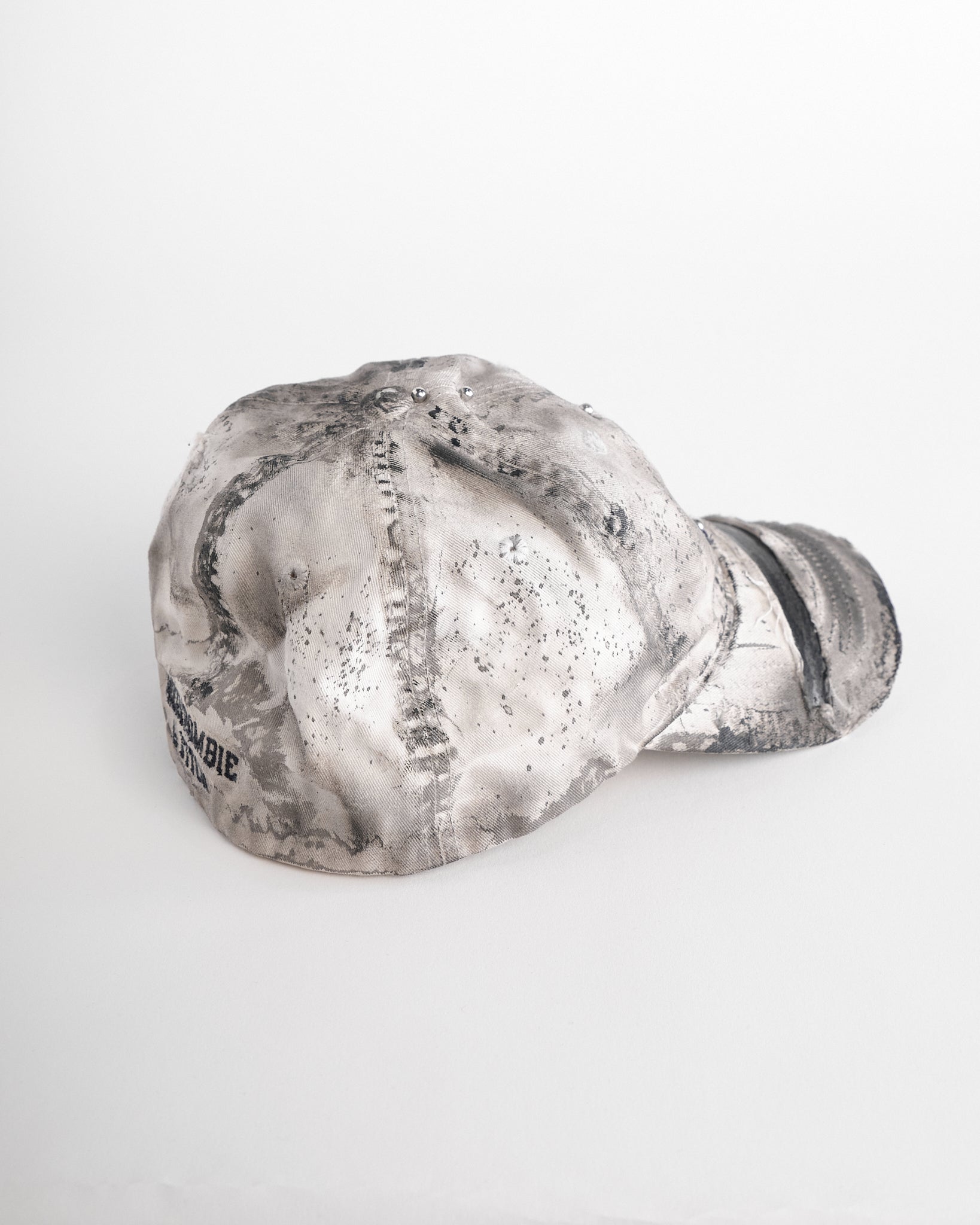 Left side of Off-white and black faded ASTROBOI* x Abercrombie hat with custom paint treatment and stainless steel piercing, handmade in NYC.
