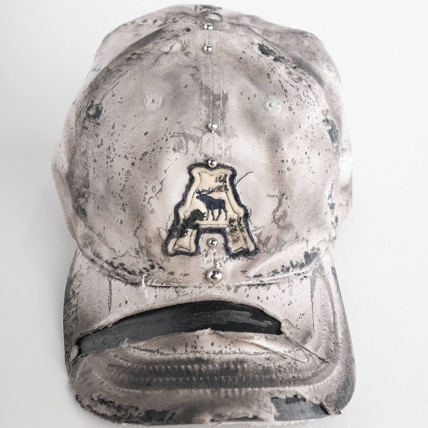 Front of Off-white and black faded ASTROBOI* x Abercrombie hat with custom paint treatment and stainless steel piercing, handmade in NYC.