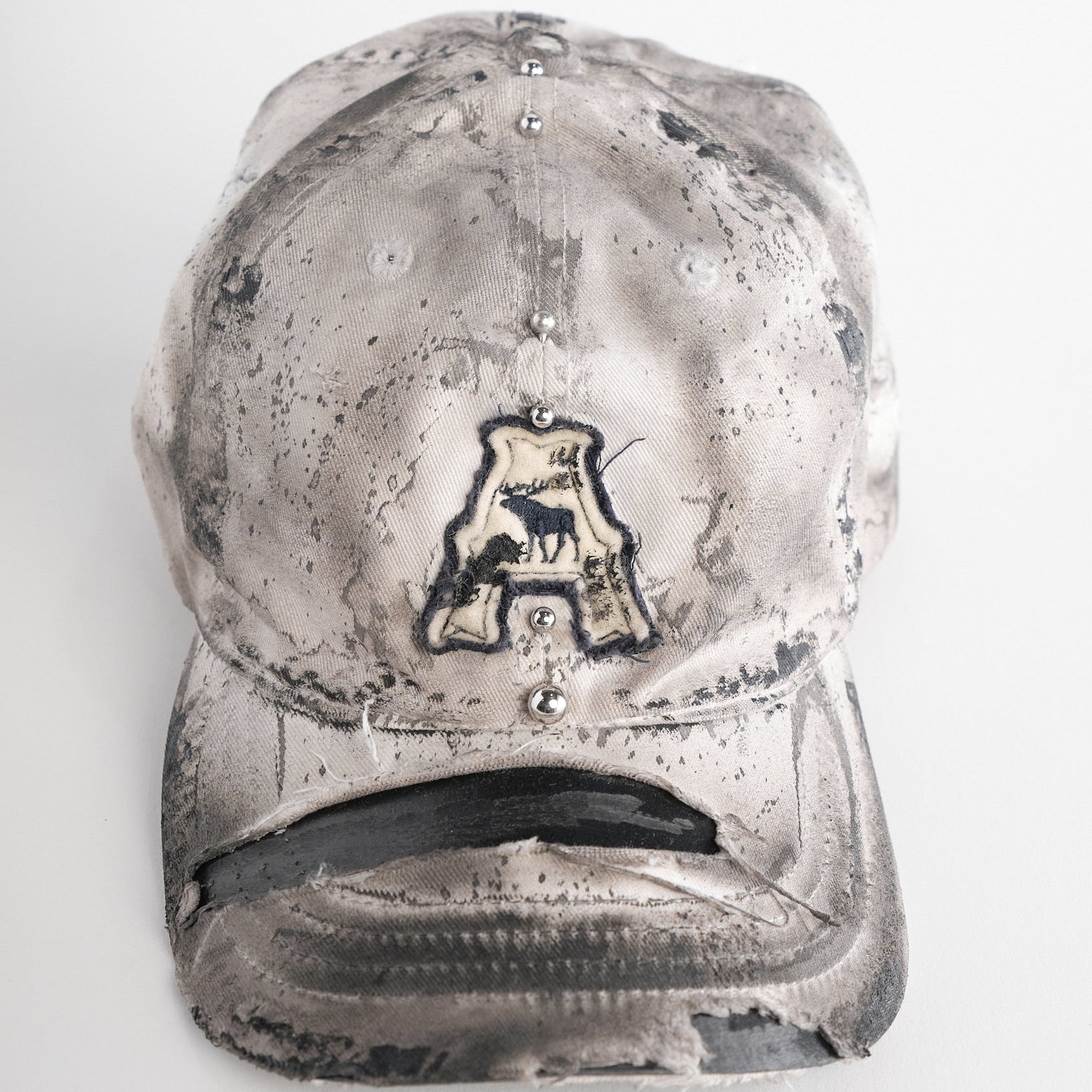 Front of Off-white and black faded ASTROBOI* x Abercrombie hat with custom paint treatment and stainless steel piercing, handmade in NYC.