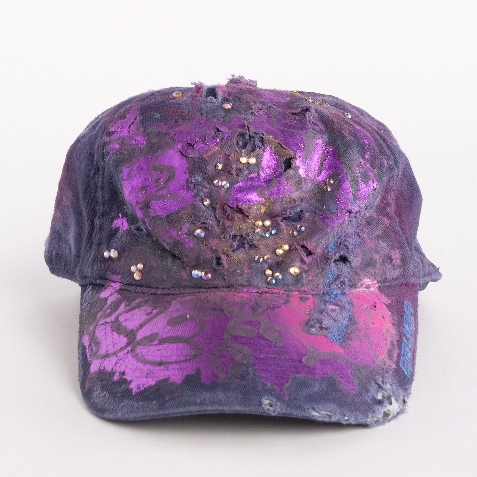 Front of ASTROBOI* x Bauer purple distressed hat with metallic paint detailing, clustered rhinestones, and closed-back fit, handmade and customized in NYC.