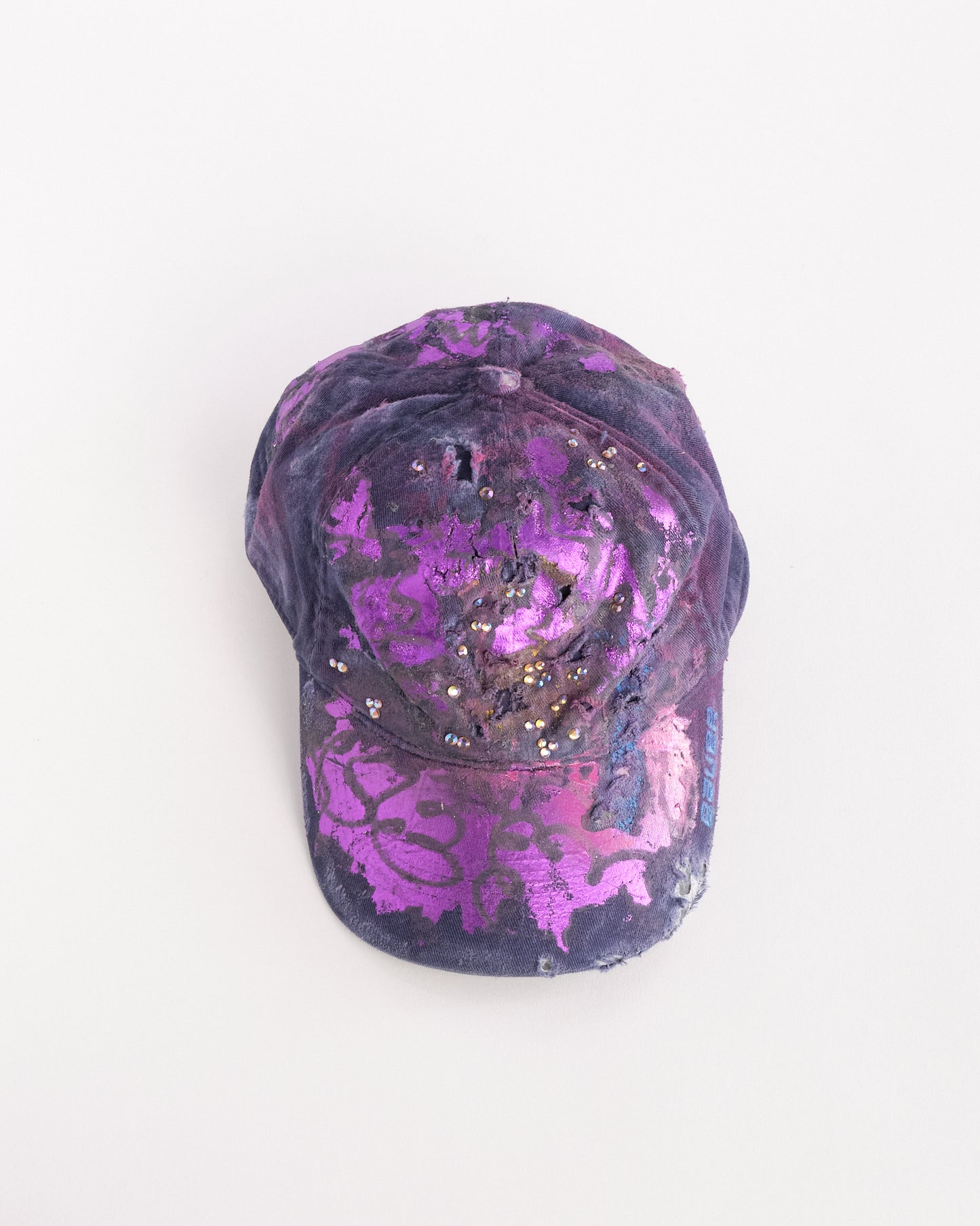 Overview of ASTROBOI* x Bauer purple distressed hat with metallic paint detailing, clustered rhinestones, and closed-back fit, handmade and customized in NYC.