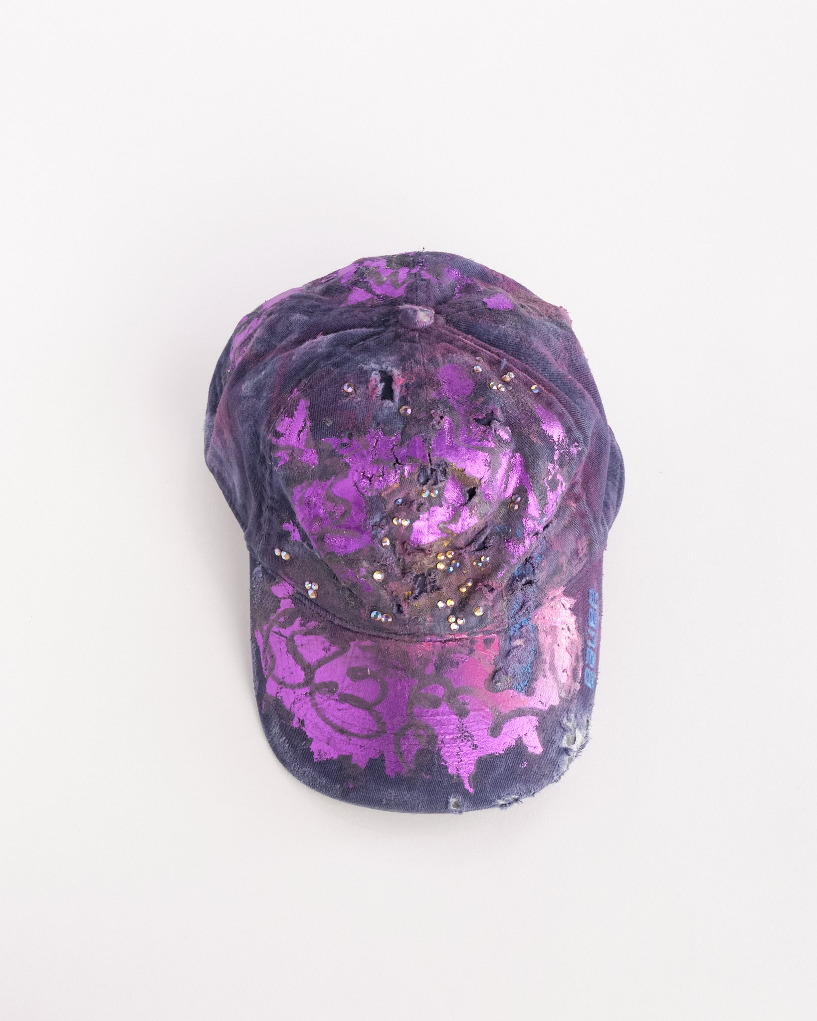 Overview of ASTROBOI* x Bauer purple distressed hat with metallic paint detailing, clustered rhinestones, and closed-back fit, handmade and customized in NYC.