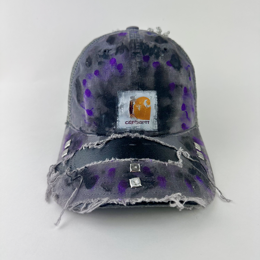 ASTROBOI* x Carhartt 'Amethyst' gray and purple distressed studded hat with Carhartt logo patch at center front, black and purple paint treatment, and silver studded deconstructed visor, front view.