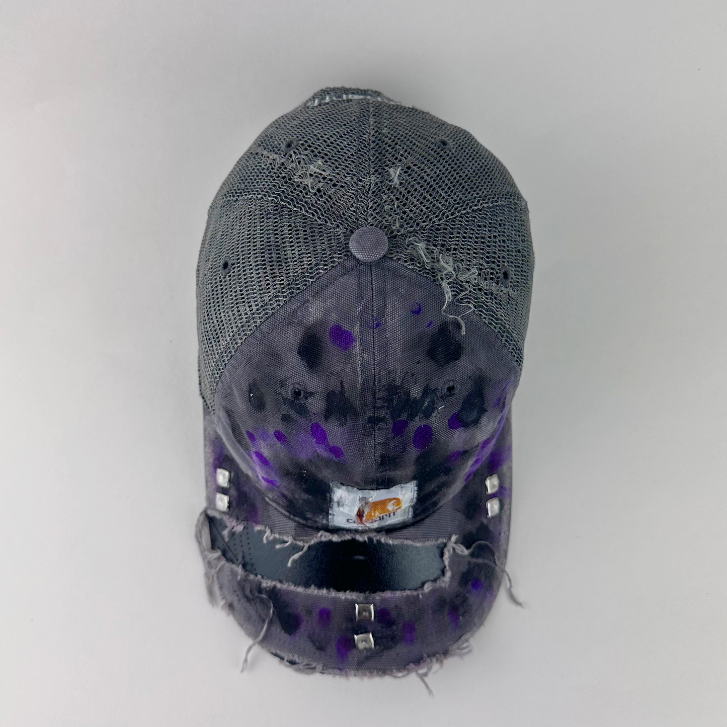 Top view of ASTROBOI* x Carhartt 'Amethyst' showing Carhartt logo patch and silver stud detail on deconstructed visor with black and purple paint treatment.
