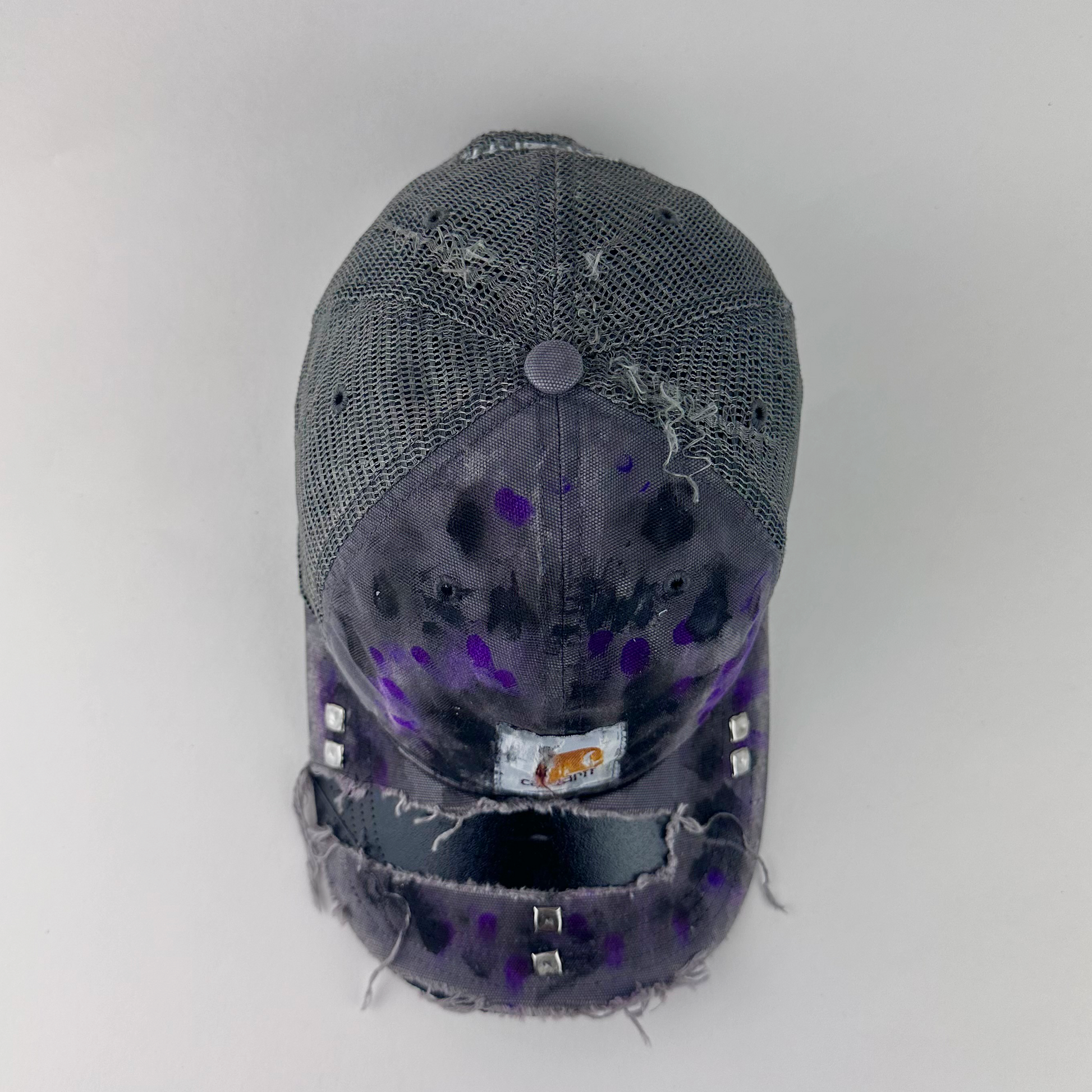 Top view of ASTROBOI* x Carhartt 'Amethyst' showing Carhartt logo patch and silver stud detail on deconstructed visor with black and purple paint treatment.