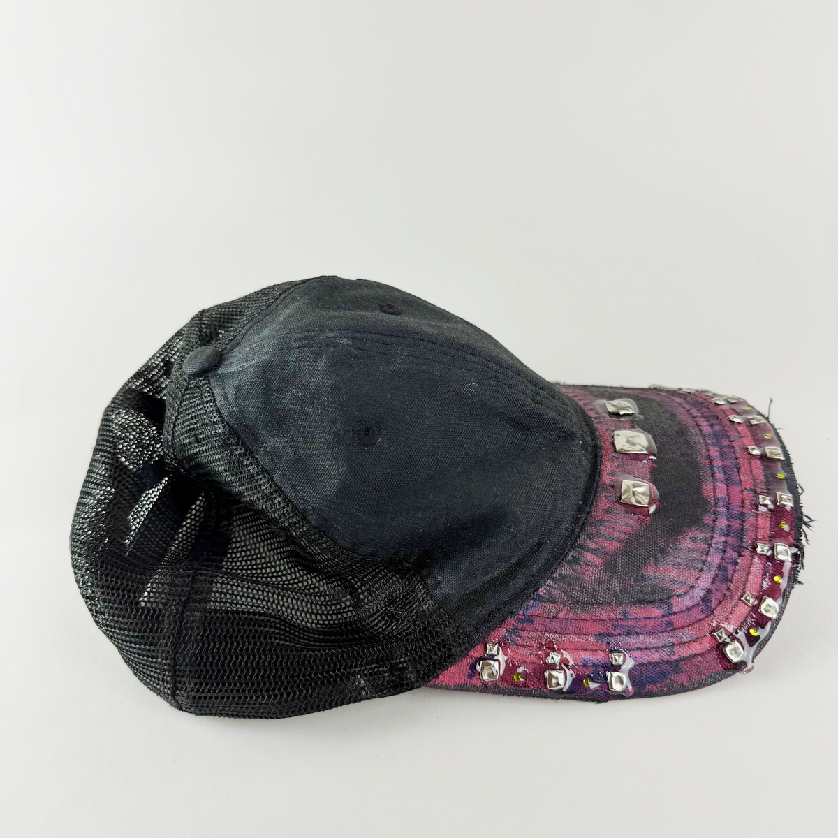 Detail of distressed maroon visor with custom paint, rhinestones, studs, and resin.
