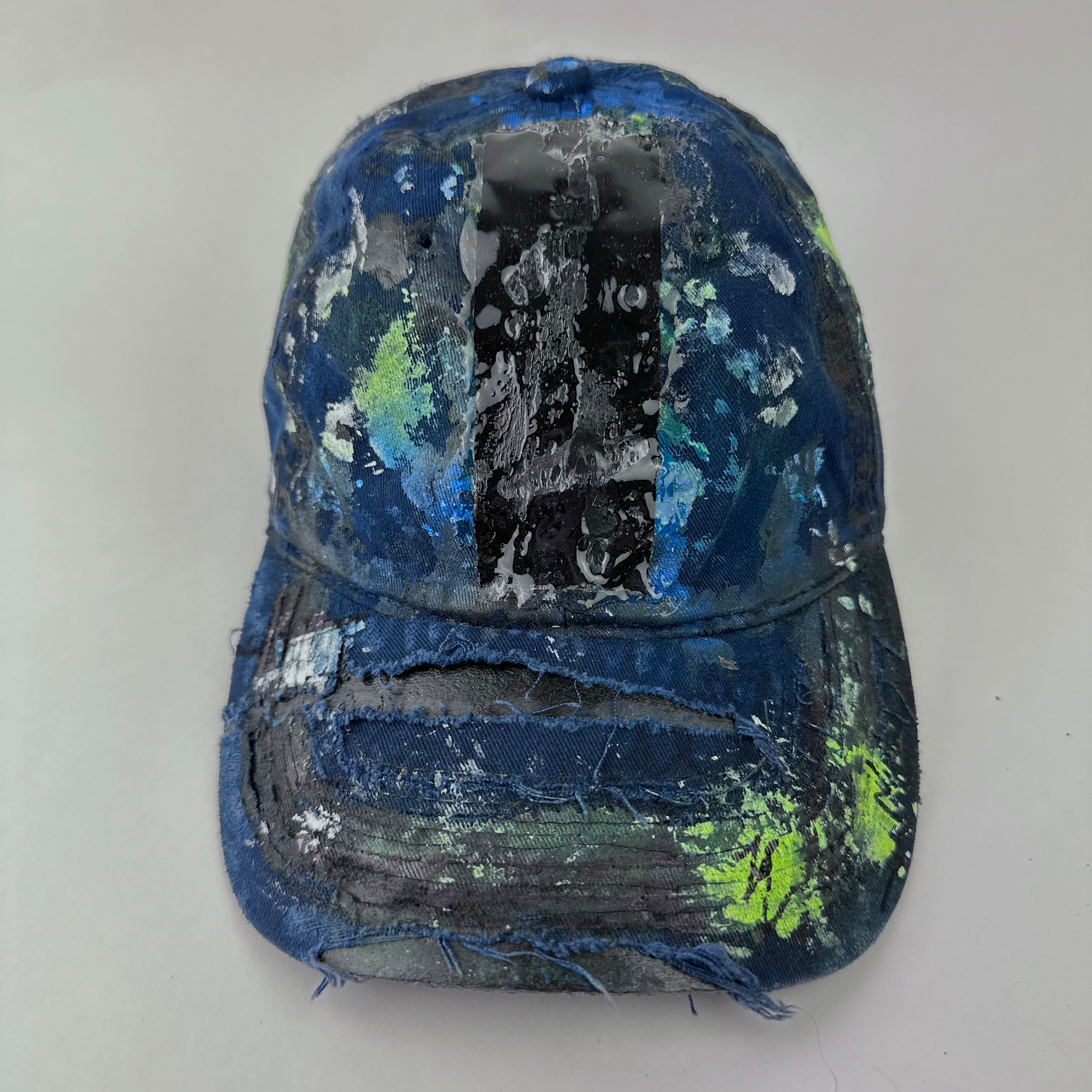 ASTROBOI* 'Coral' blue distressed painted cap with black, white, and blue speckled paint splatter treatment and deconstructed visor with melted duct tape and 3D resin detail, front view.