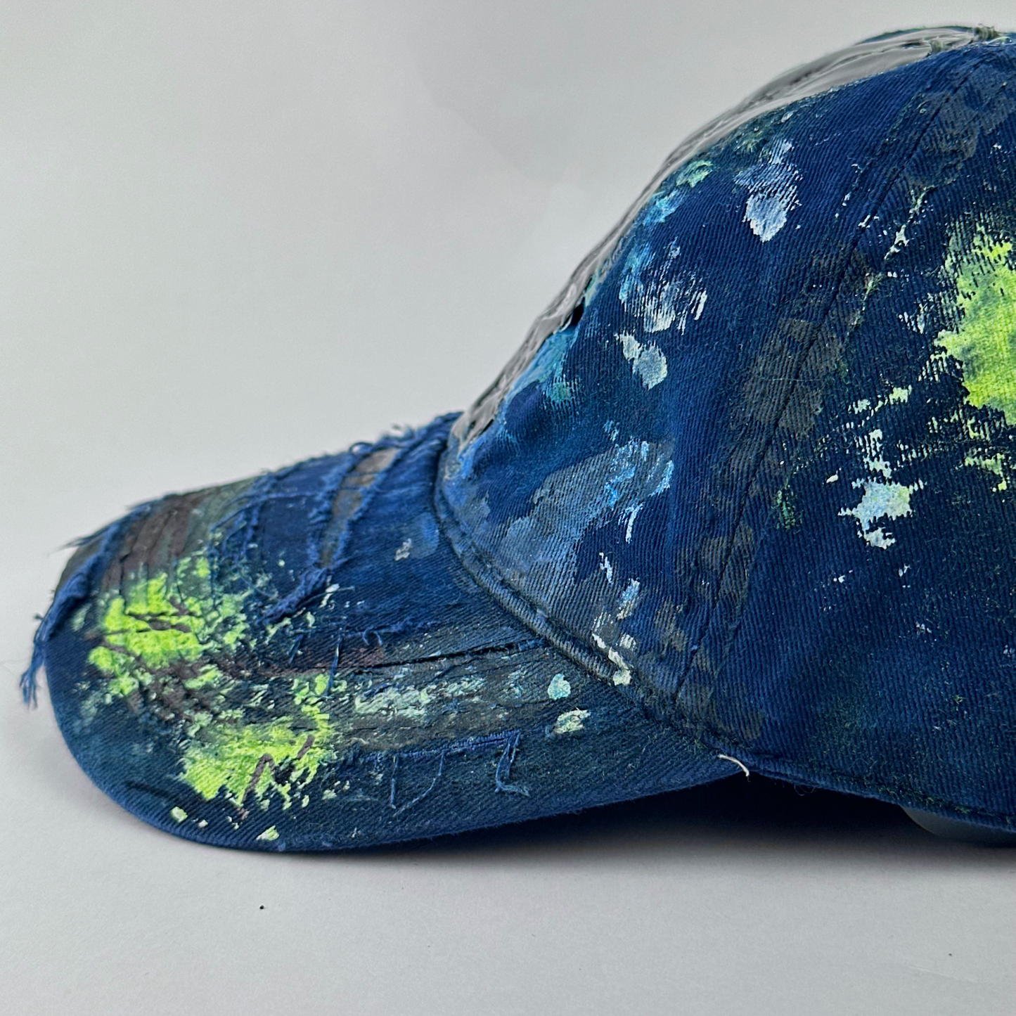 Left side visor detail of ASTROBOI* 'Coral' showing distressing and speckled paint splatter treatment on blue base.
