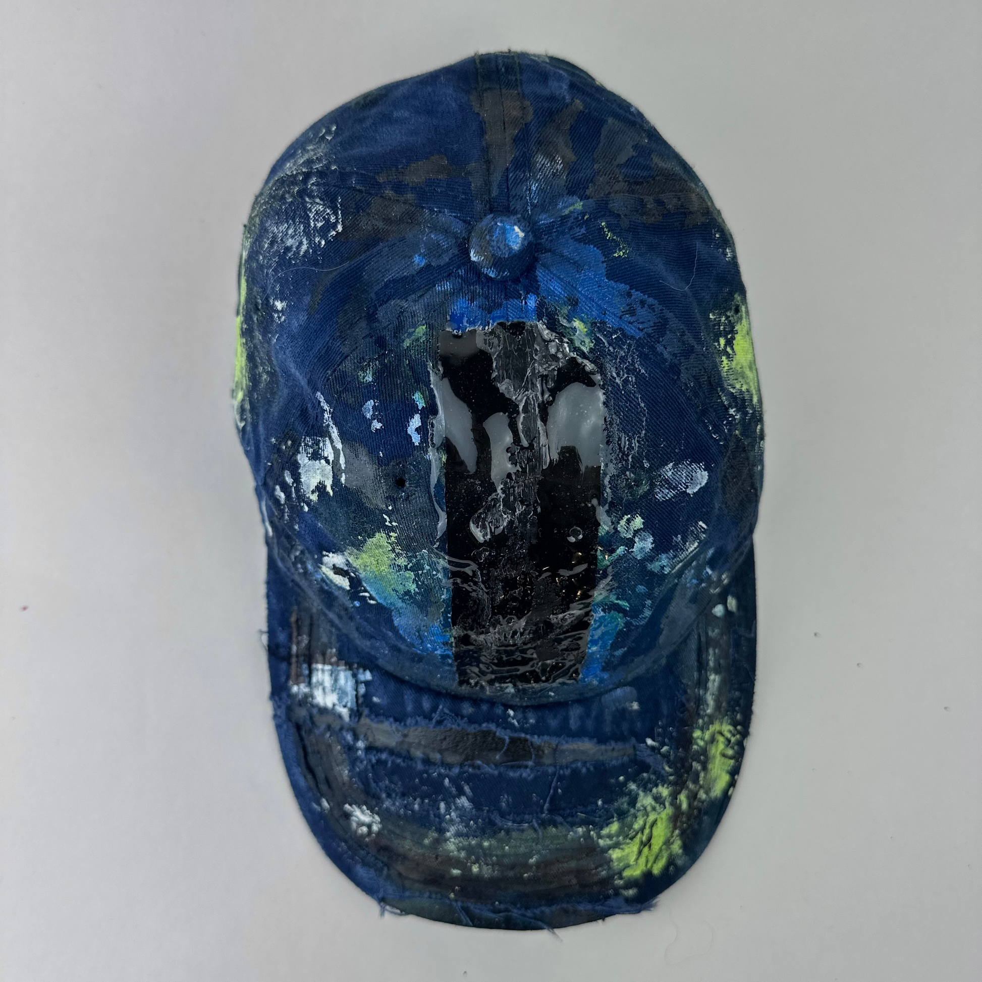 Top view oof ASTROBOI* 'Coral' showing black, white, and blue speckled paint splatter and melted duct tape detail sealed under 3D wet resin on deconstructed visor.