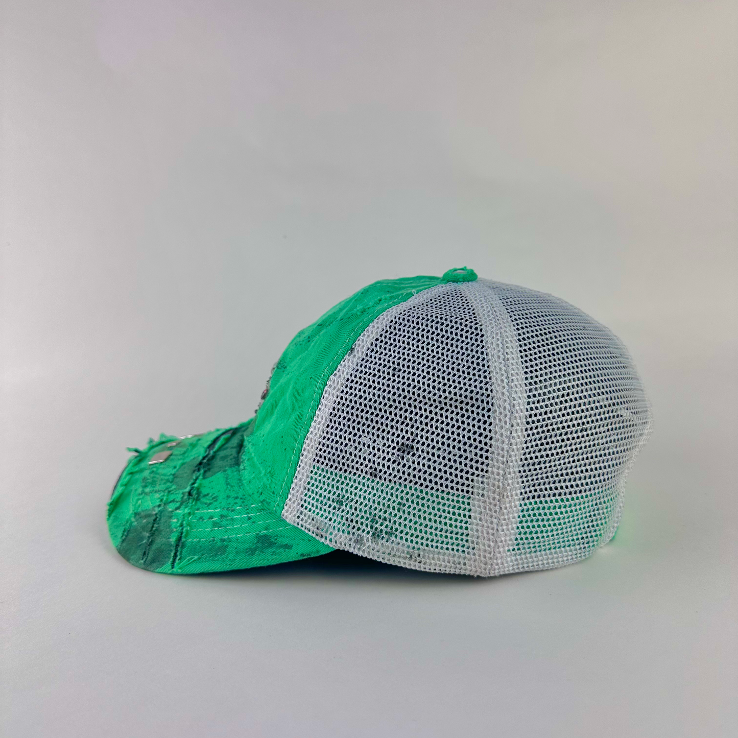 Left side detail of ASTROBOI* x Costa del Mar 'Jade' showing rhinestone embellishment, silver stud visor detail, and black stained paint treatment on Y2K green hat.