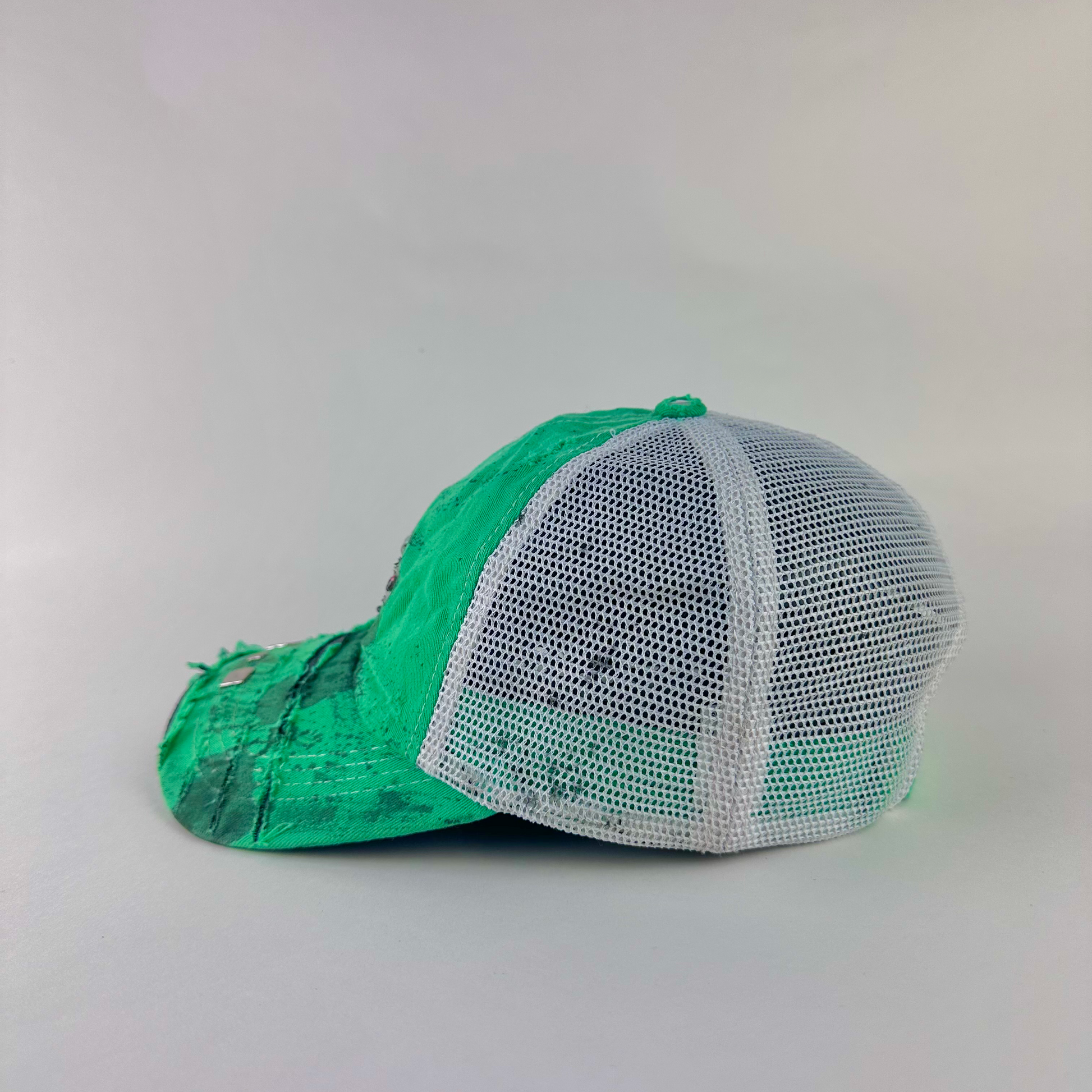 Left side detail of ASTROBOI* x Costa del Mar 'Jade' showing rhinestone embellishment, silver stud visor detail, and black stained paint treatment on Y2K green hat.
