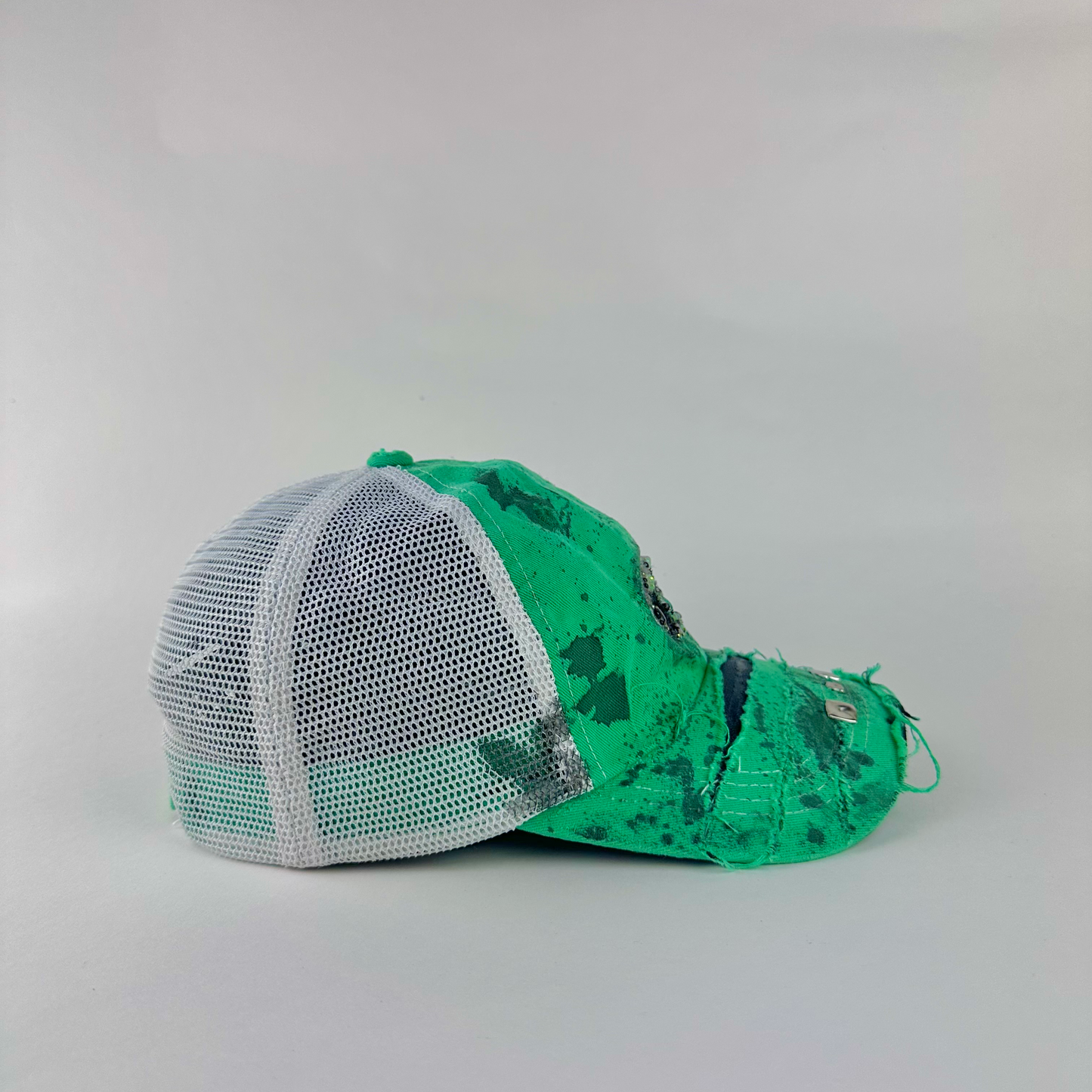 Right side detail of ASTROBOI* x Costa del Mar 'Jade' showing silver studded deconstructed visor and black stained paint treatment on green trucker base.