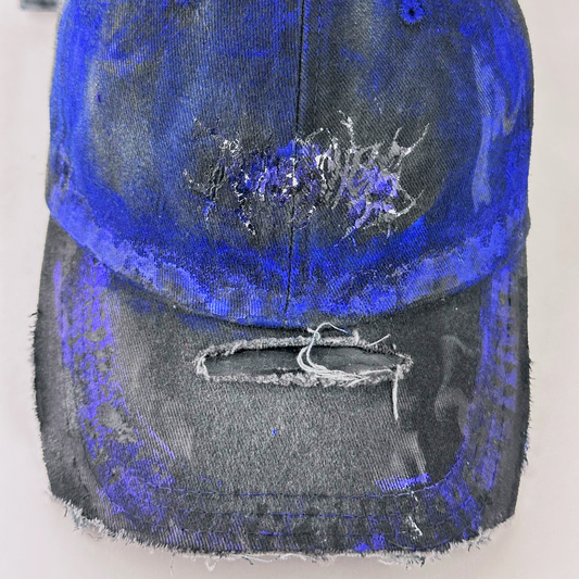 Close-up of ASTROBOI* 'Damian' showing indie barbed wire design detail and custom blue haze paint treatment on gray and black distressed fabric.