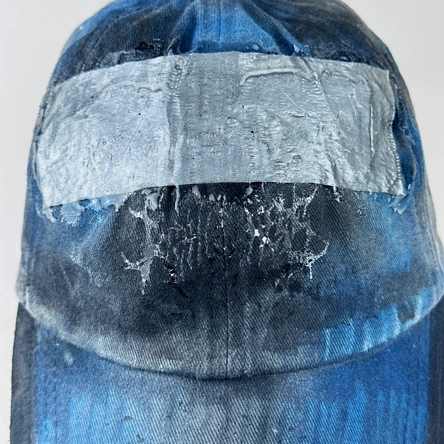 Close-up of ASTROBOI* 'Duct' showing barbed wire design detail and melted duct tape sealed under clear resin on distressed blue denim fabric.