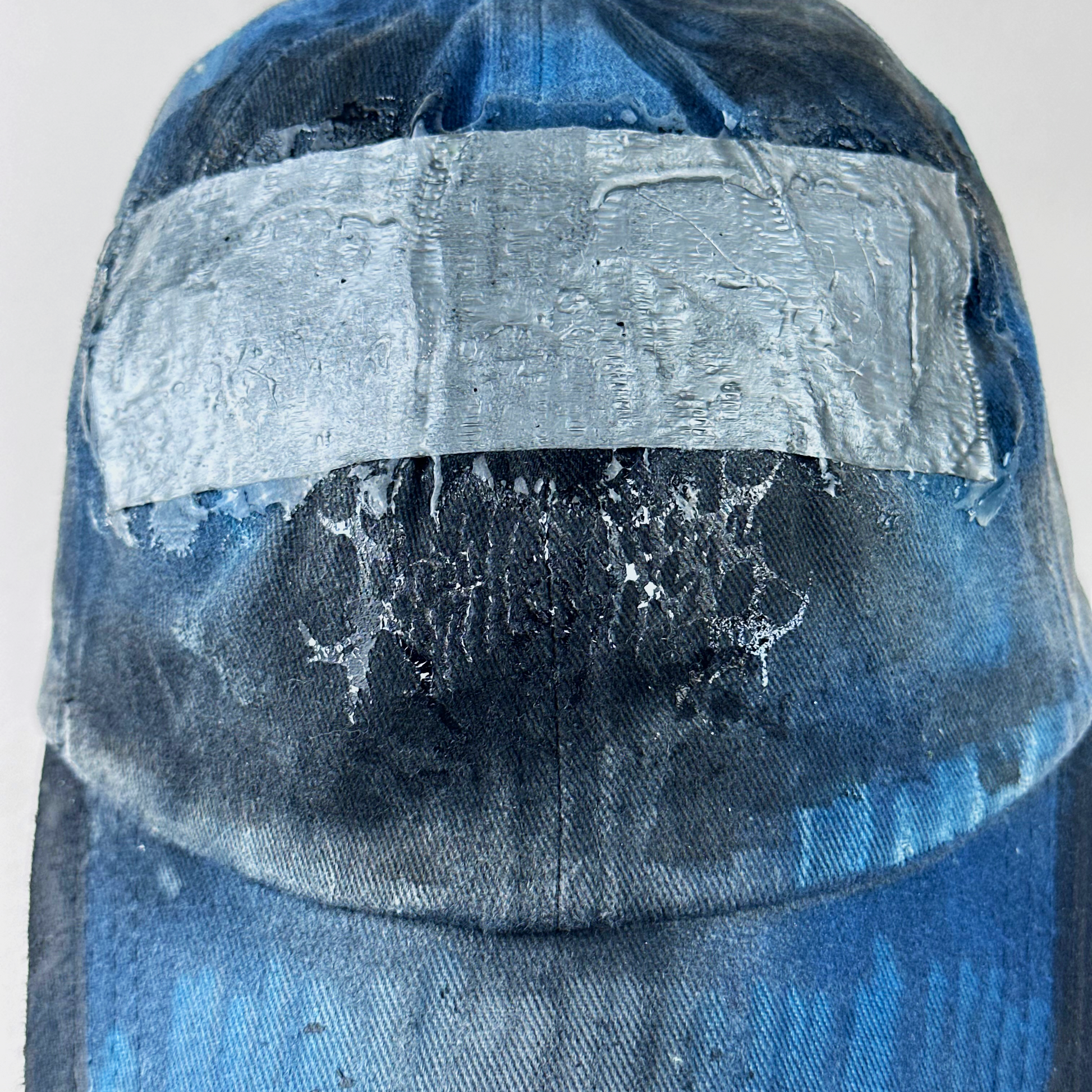 Close-up of ASTROBOI* 'Duct' showing barbed wire design detail and melted duct tape sealed under clear resin on distressed blue denim fabric.