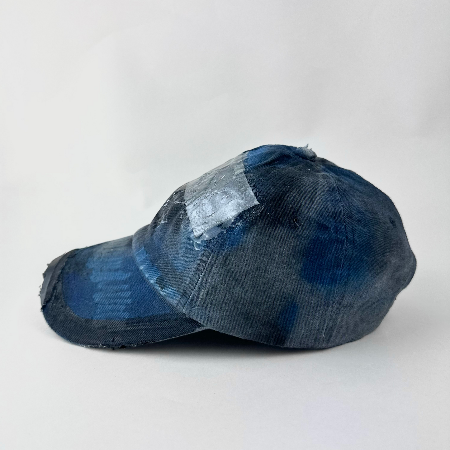 Left side detail of ASTROBOI* 'Duct' showing deconstructed visor and melted duct tape resin detail on distressed blue denim hat.