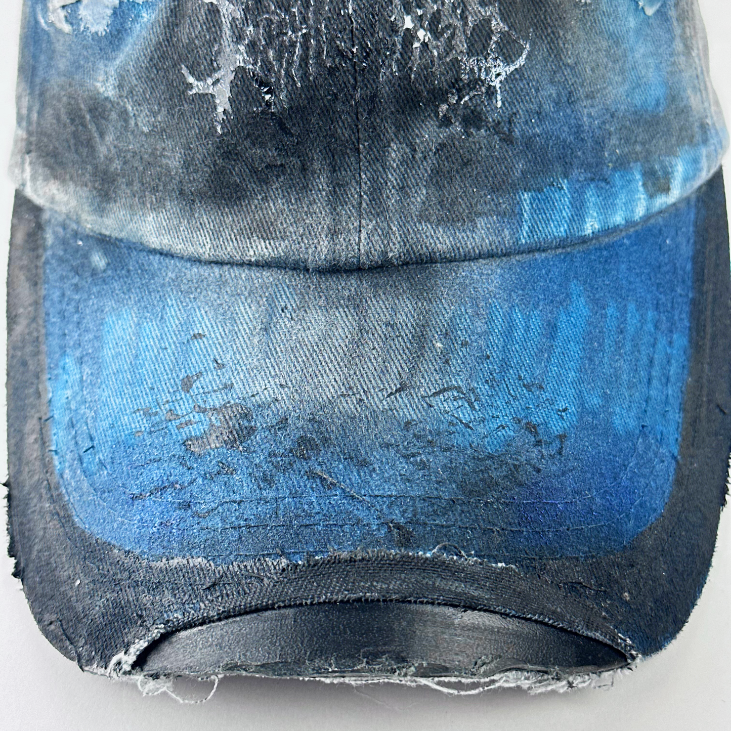 Close-up of visor detail on ASTROBOI* 'Duct' showing barbed wire design detail and melted duct tape sealed under clear resin on distressed blue denim fabric.