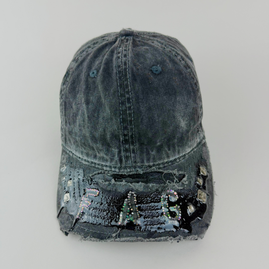 Close-up of multicolor rhinestone “FAG” lettering in silver, pink, and green on black denim.