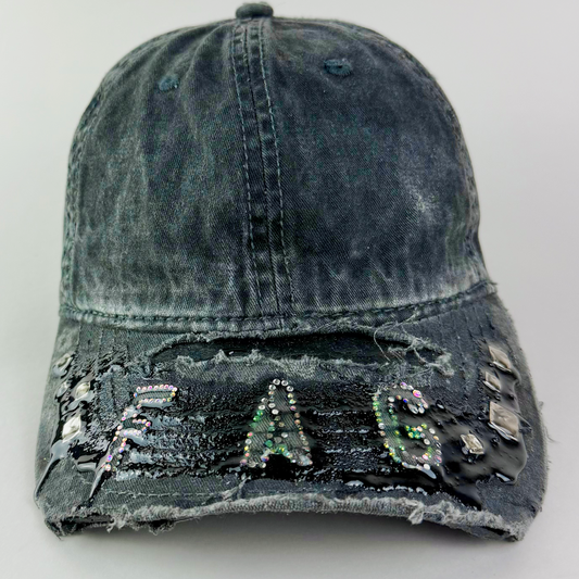 Close-up of multicolor rhinestone “FAG” lettering in silver, pink, and green on black denim.