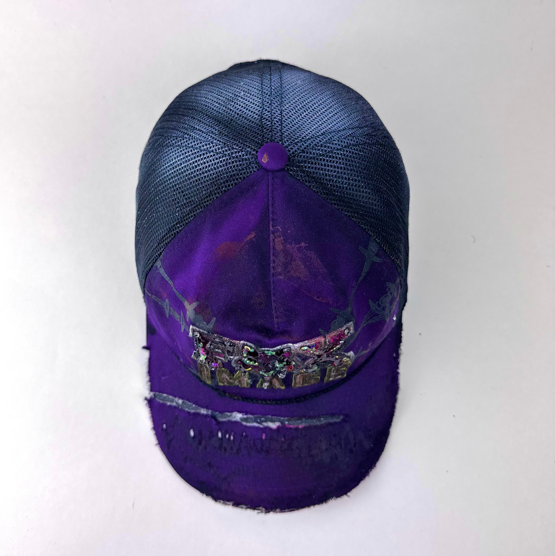 Top view of ASTROBOI* x Fox Racing 'Barbed Wire' showing deconstructed visor detail and multicolored rhinestone embellishment on purple hat.
