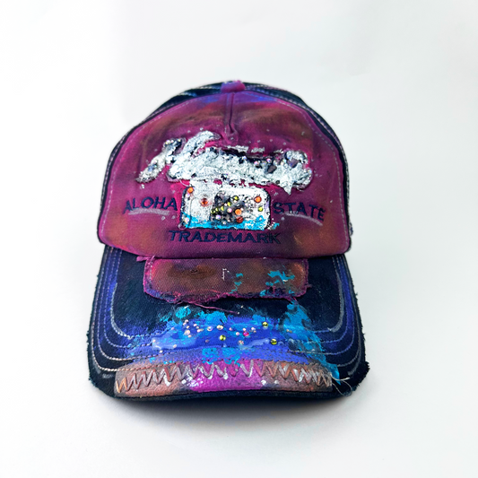 ASTROBOI* 'Hibiscus' red and black Y2K Hawaii rhinestone hat with silver embroidered 'Hawaii ALOHA STATE TRADEMARK' text, purple and pink paint splatter, and metallic rhinestone embellishments, front view 2.