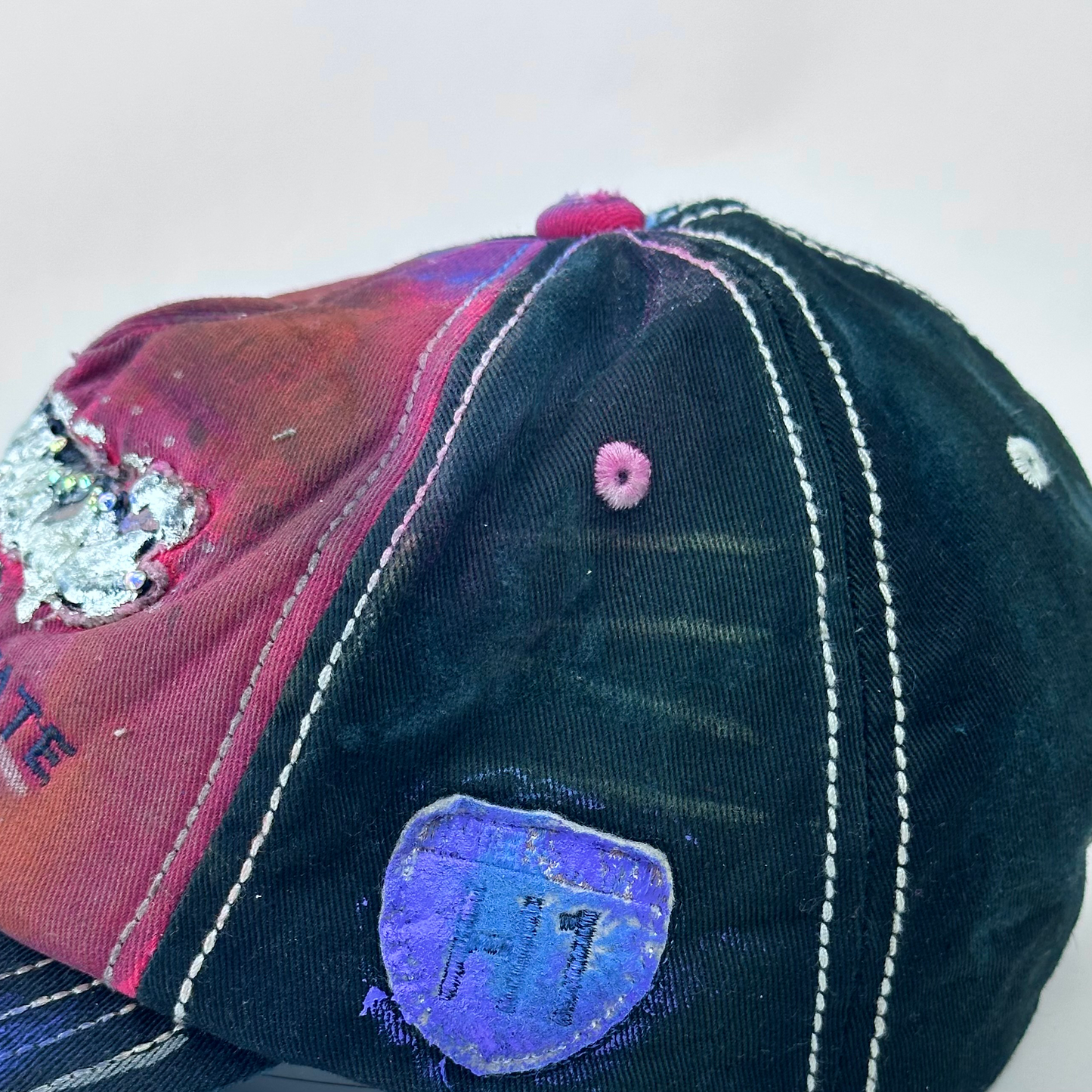ASTROBOI* 'Tropicale' red and black Y2K Hawaii rhinestone hat with silver embroidered 'Hawaii ALOHA STATE TRADEMARK' text, purple and pink paint splatter, and metallic rhinestone embellishments, right side logo patch.