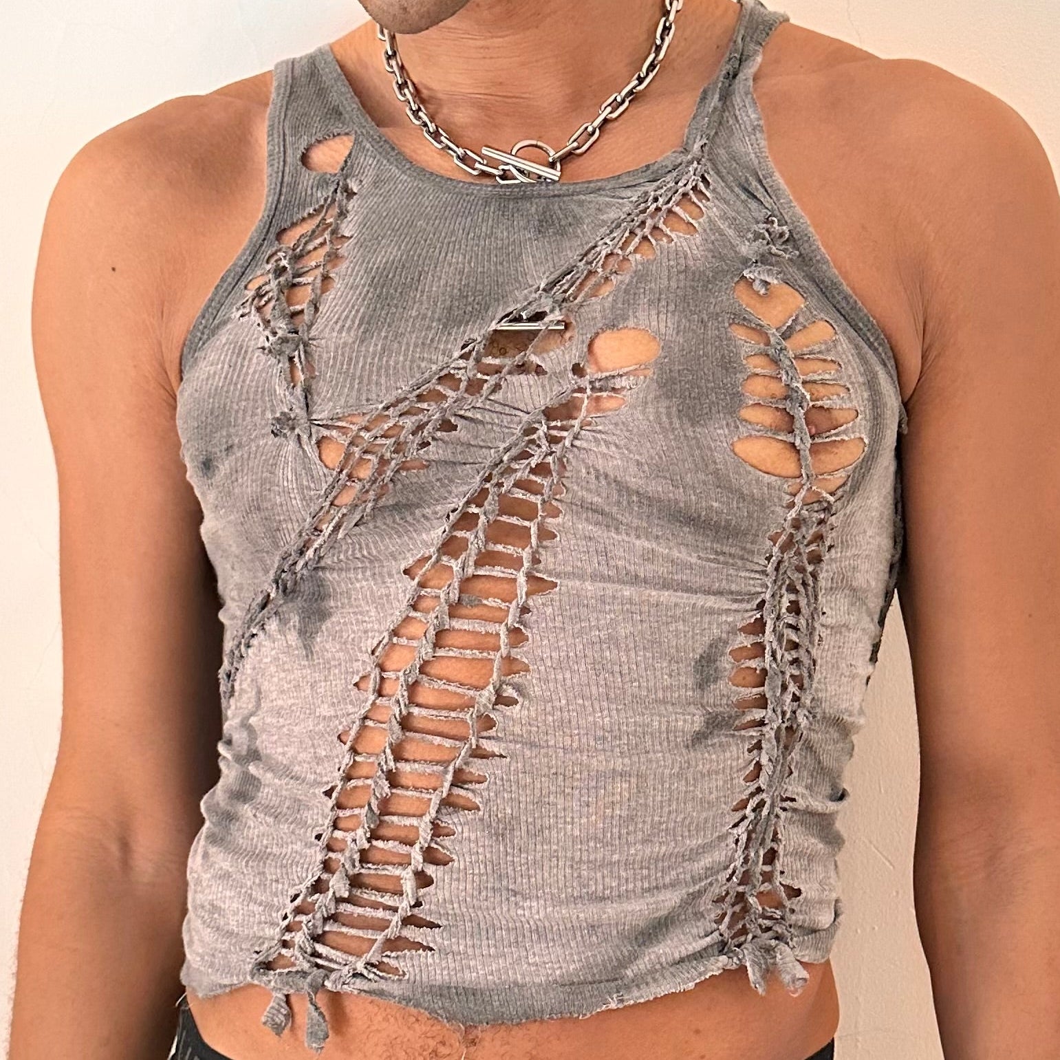Close-up of ASTROBOI* x Gildan 'Stone' showing hand-braided construction, knot and cut-out detailing, and tonal sun-faded paint treatment on antique gray cotton.