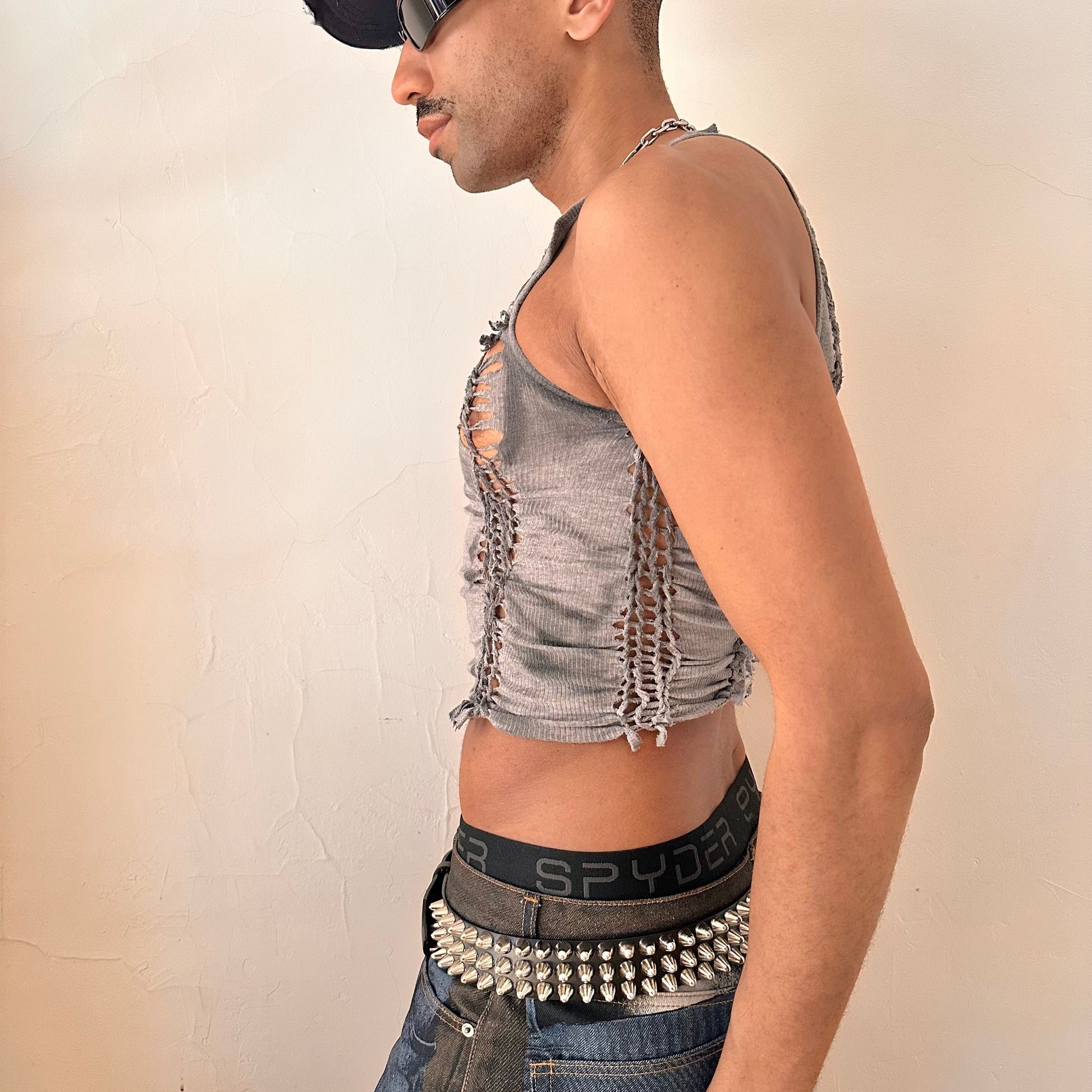 Left side detail of ASTROBOI* x Gildan 'Stone' showing hand-braided arrangement, knot detail, and sun-faded tonal paint treatment on cropped gray tank.