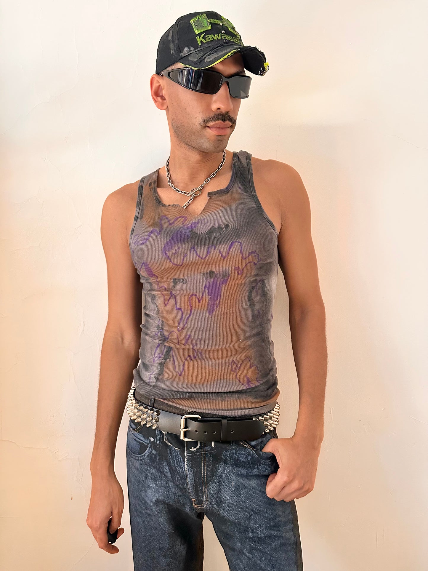 Styled image of ASTROBOI* x Gildan 'Graffiti' gray ribbed slim-fit tank top with hand-painted purple, white, black, and orange abstract graffiti design and intentional raw rip at the collar, customized at ASTROBOI* STUDIO in NYC.