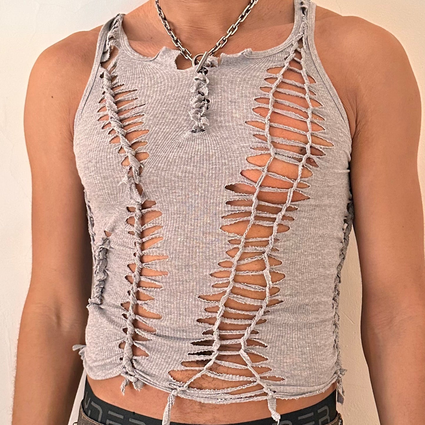 Close-up of ASTROBOI* 'Morpheus' showing hand-braided construction, knot, and cut-out detailing on soft gray cotton fabric.