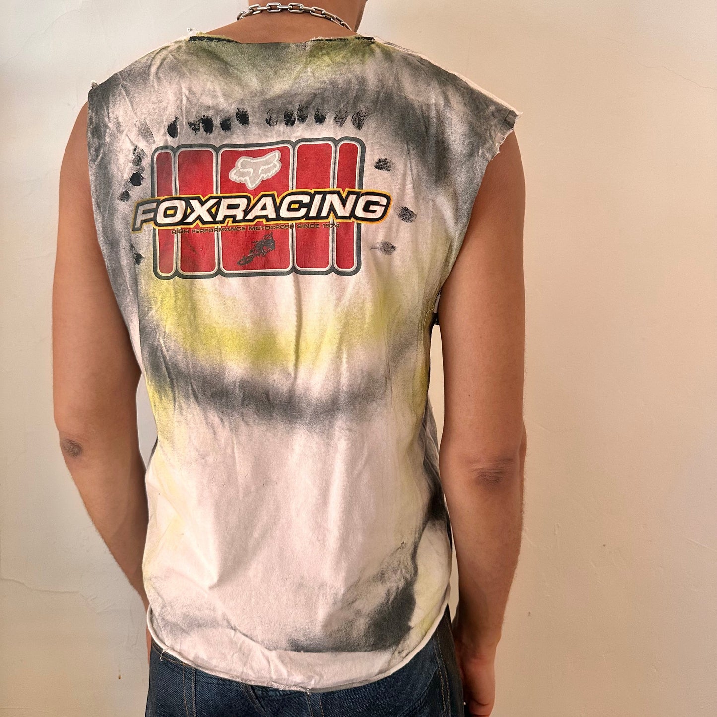 ASTROBOI* x Fox Racing white airbrushed motocross tank top, rear view showing black and acid yellow airbrush streak design, worn by male model.