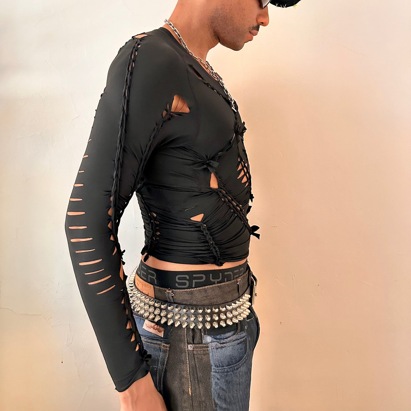 Right side detail of ASTROBOI* 'LEO' showing braided twist and slash construction on close-fitting black spandex base.