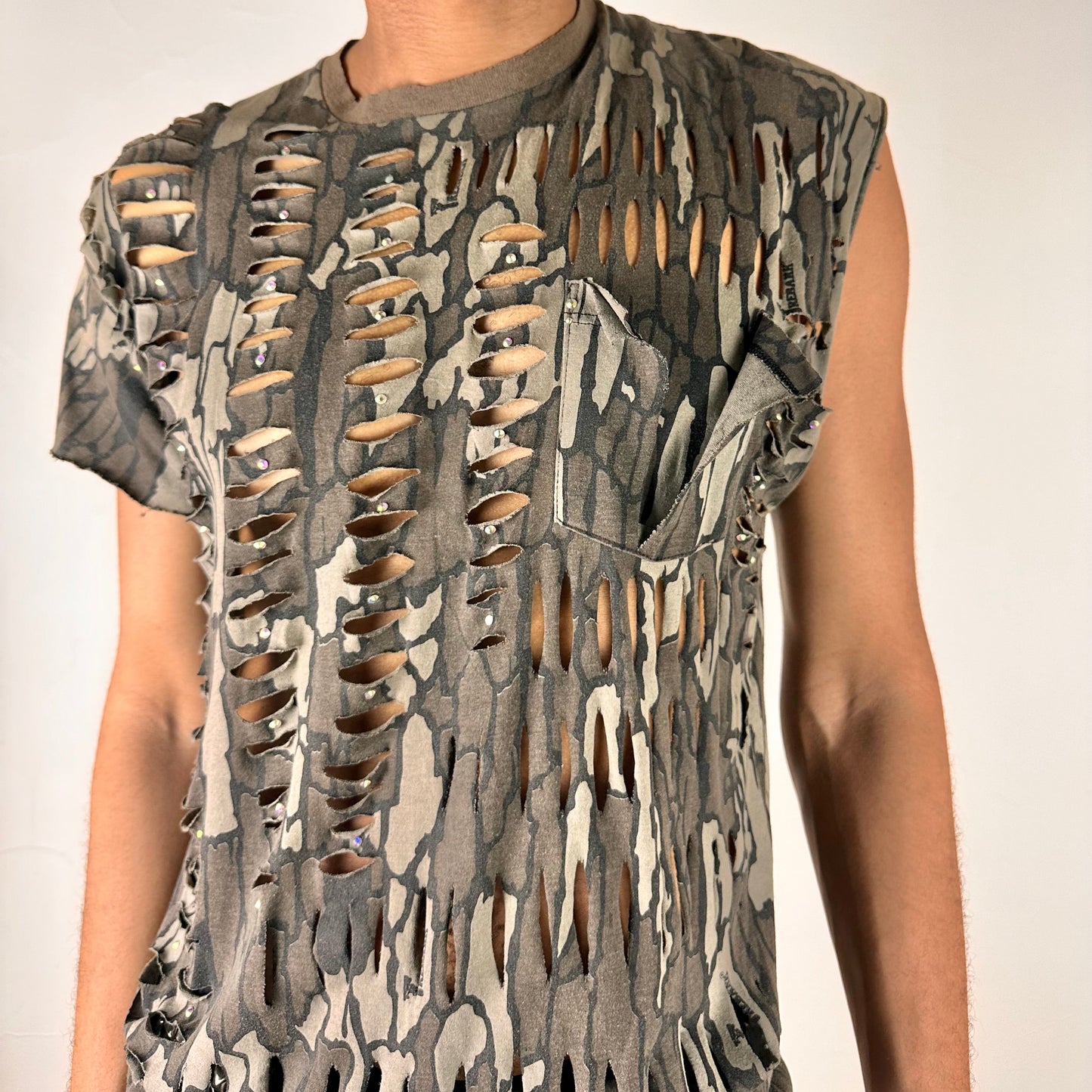 Close-up of ASTROBOI* 'Maelstrom' showing rainbow rhinestone detailing and deconstructed pocket on Real Tree camo fabric.