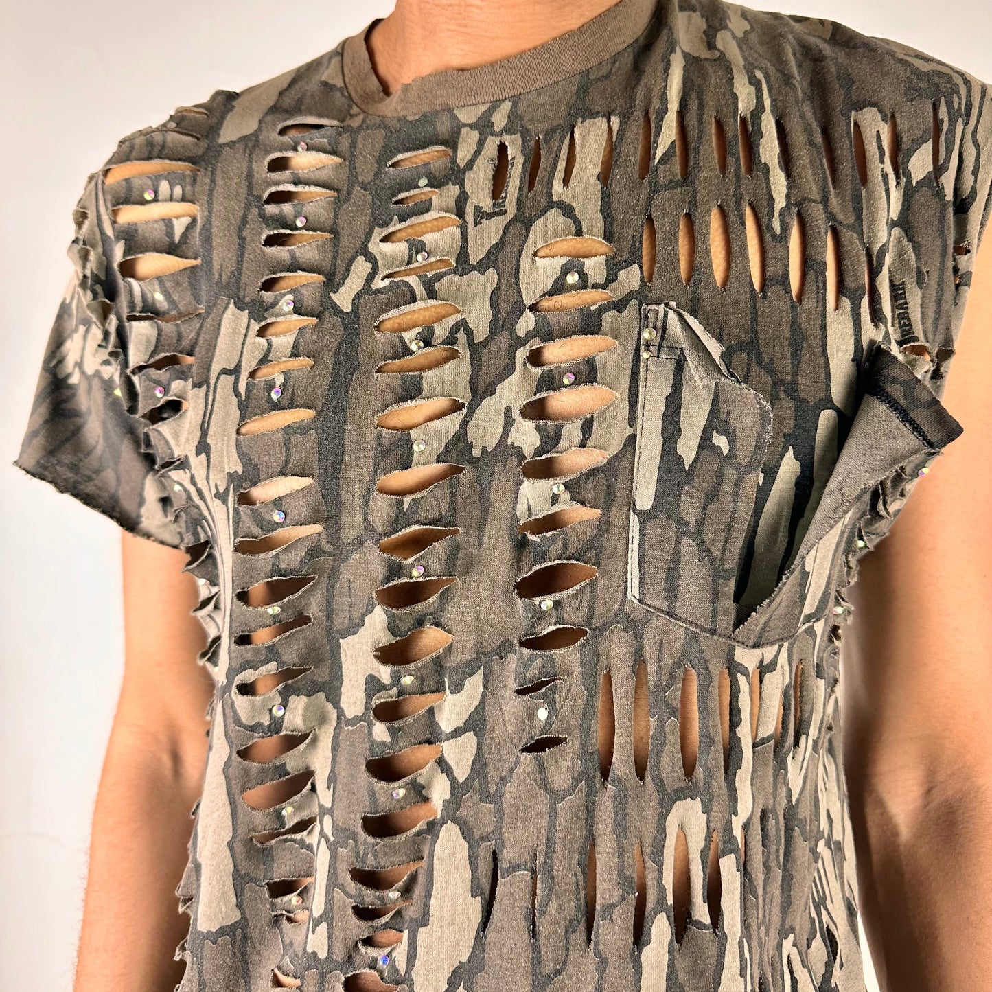 Close-up of ASTROBOI* 'Maelstrom' showing rainbow rhinestone detailing and deconstructed pocket on Real Tree camo fabric.