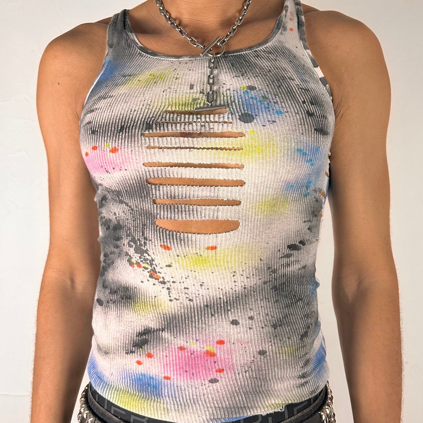 Close up of ASTROBOI* x Hanes 'HEAVEN' white ribbed cotton tank top with hand-painted pink, yellow, black, and blue abstract graphic, deconstructed cut-outs along chest and sides, customized at ASTROBOI* STUDIO in NYC.
