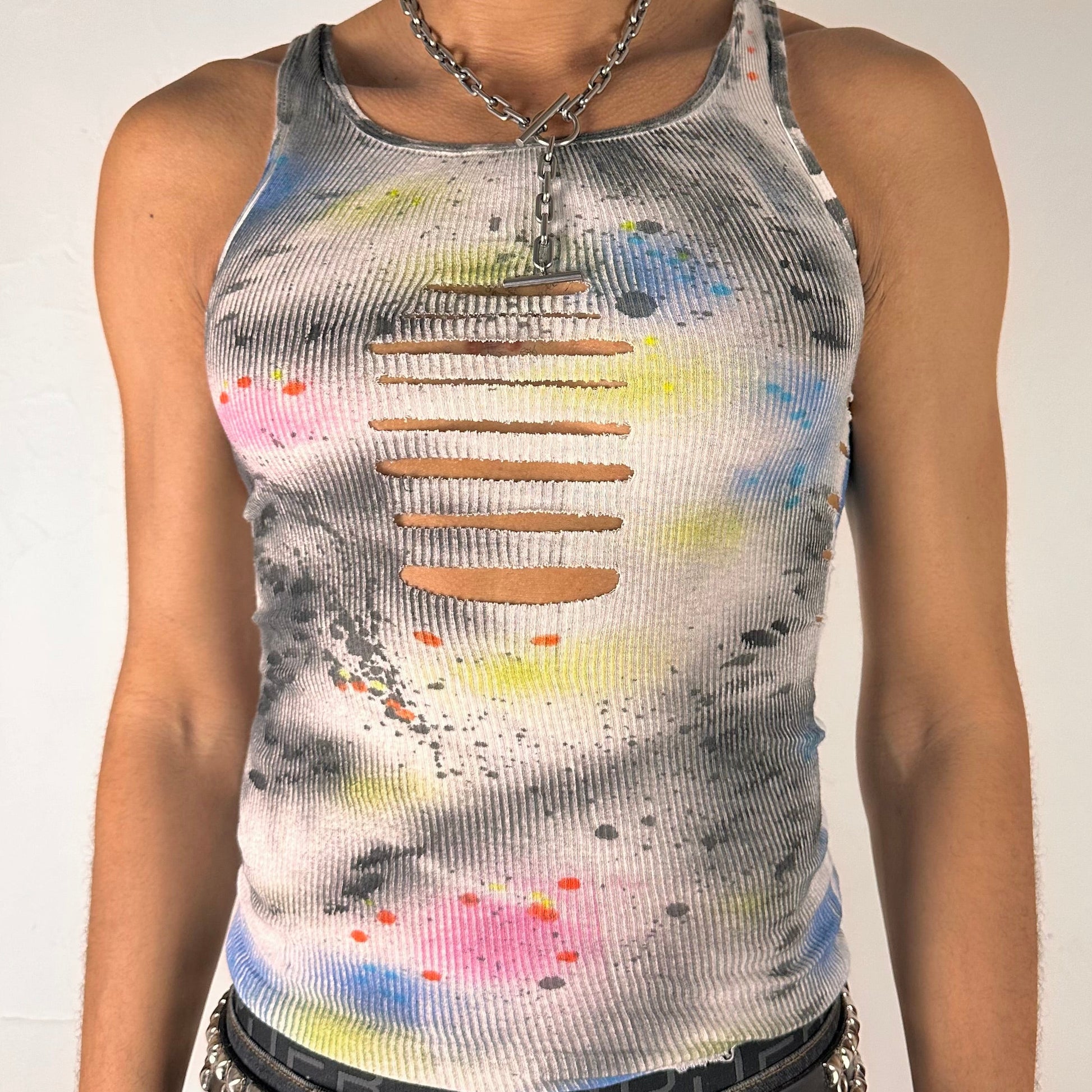 Close up of ASTROBOI* x Hanes 'HEAVEN' white ribbed cotton tank top with hand-painted pink, yellow, black, and blue abstract graphic, deconstructed cut-outs along chest and sides, customized at ASTROBOI* STUDIO in NYC.