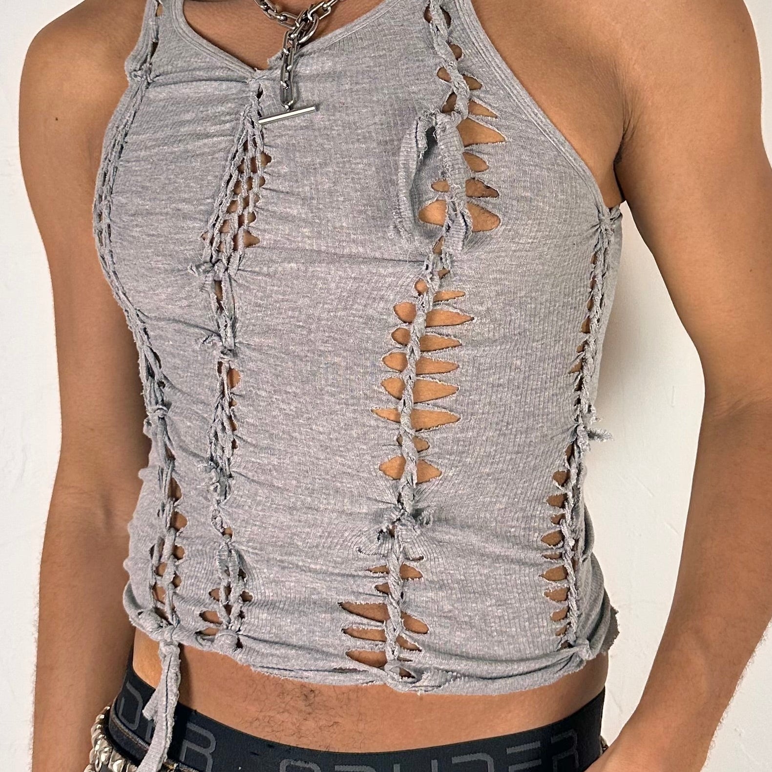 Close-up of ASTROBOI* 'Concrete' showing hand-braided twist construction, slash, and knot detailing on soft gray cotton fabric.