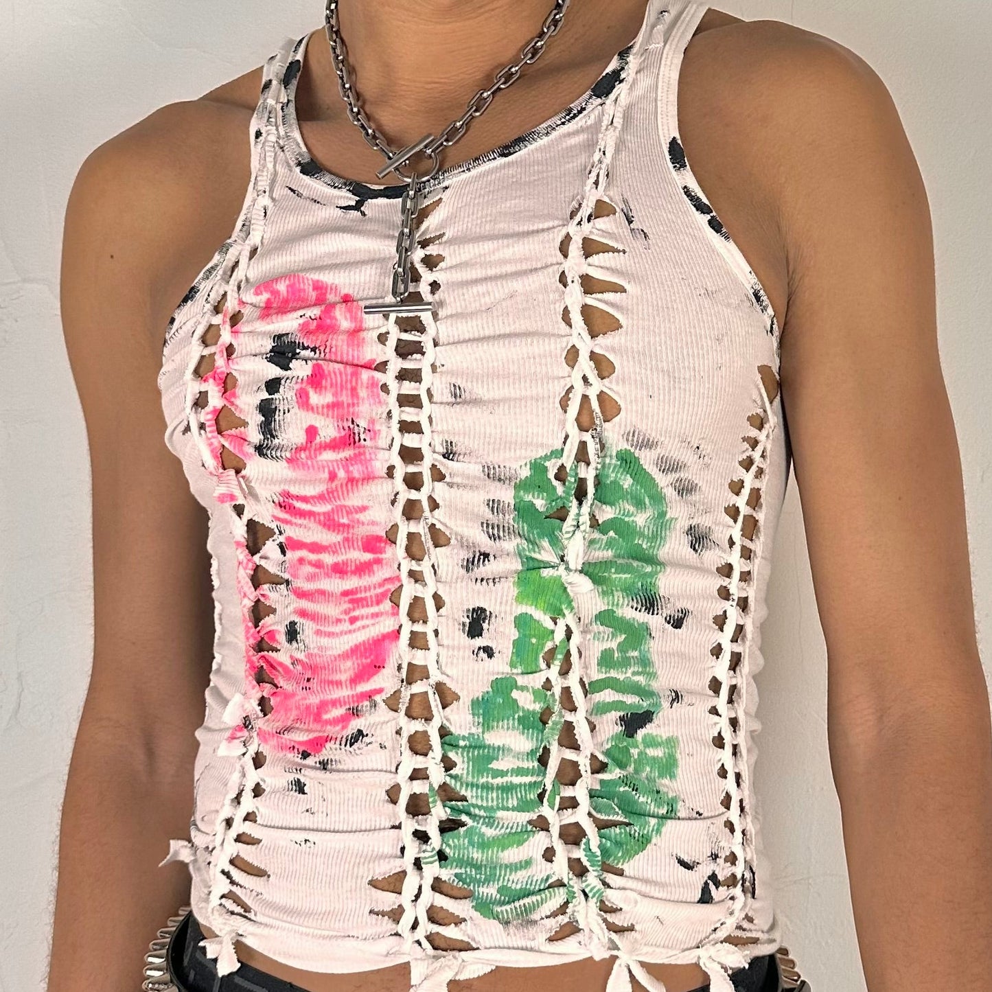 Close-up of ASTROBOI* x Calvin Klein 'Mile in Our Shoes' showing hand-braided front construction and pink and green footprint paint design with black specks on white cotton.