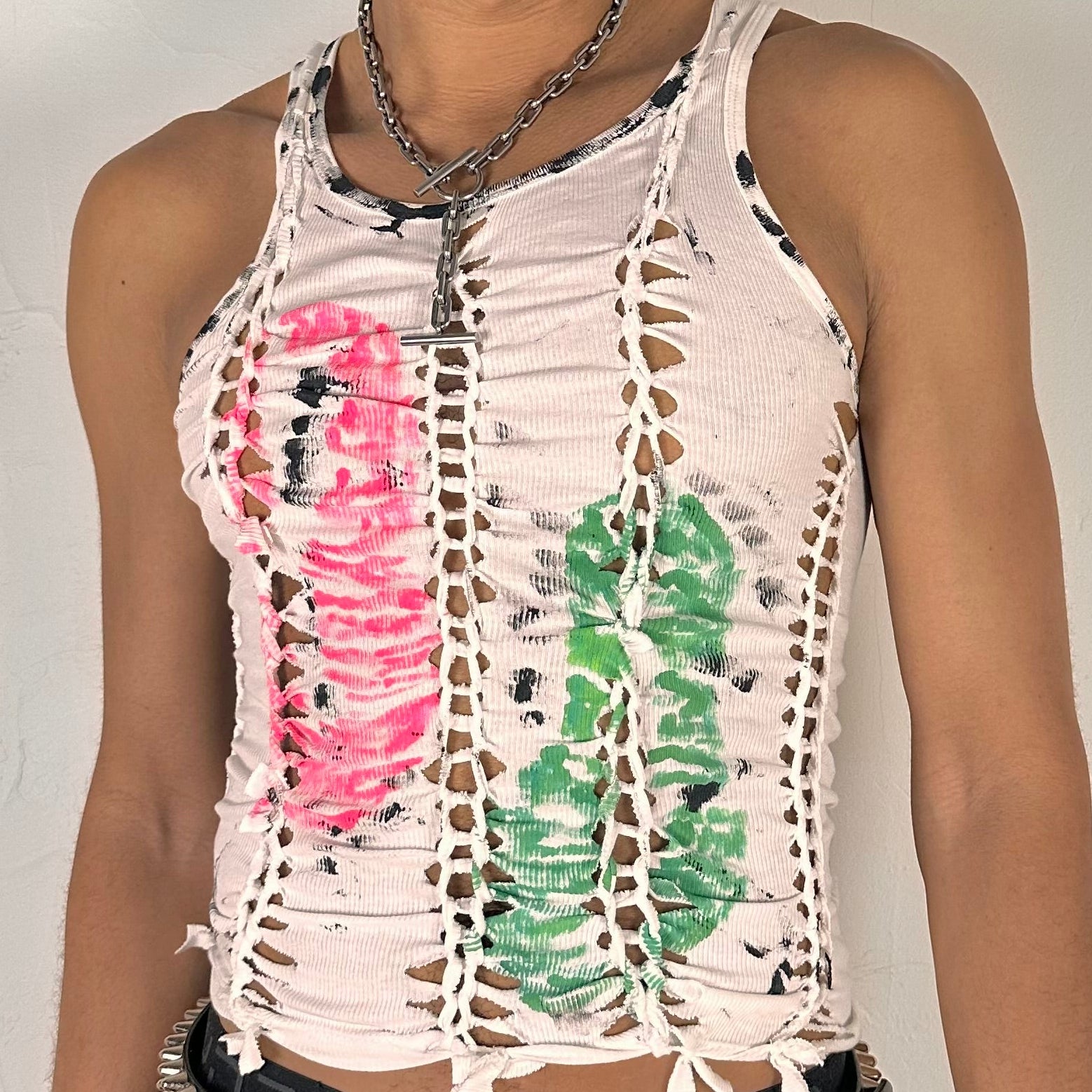 Close-up of ASTROBOI* x Calvin Klein 'Mile in Our Shoes' showing hand-braided front construction and pink and green footprint paint design with black specks on white cotton.