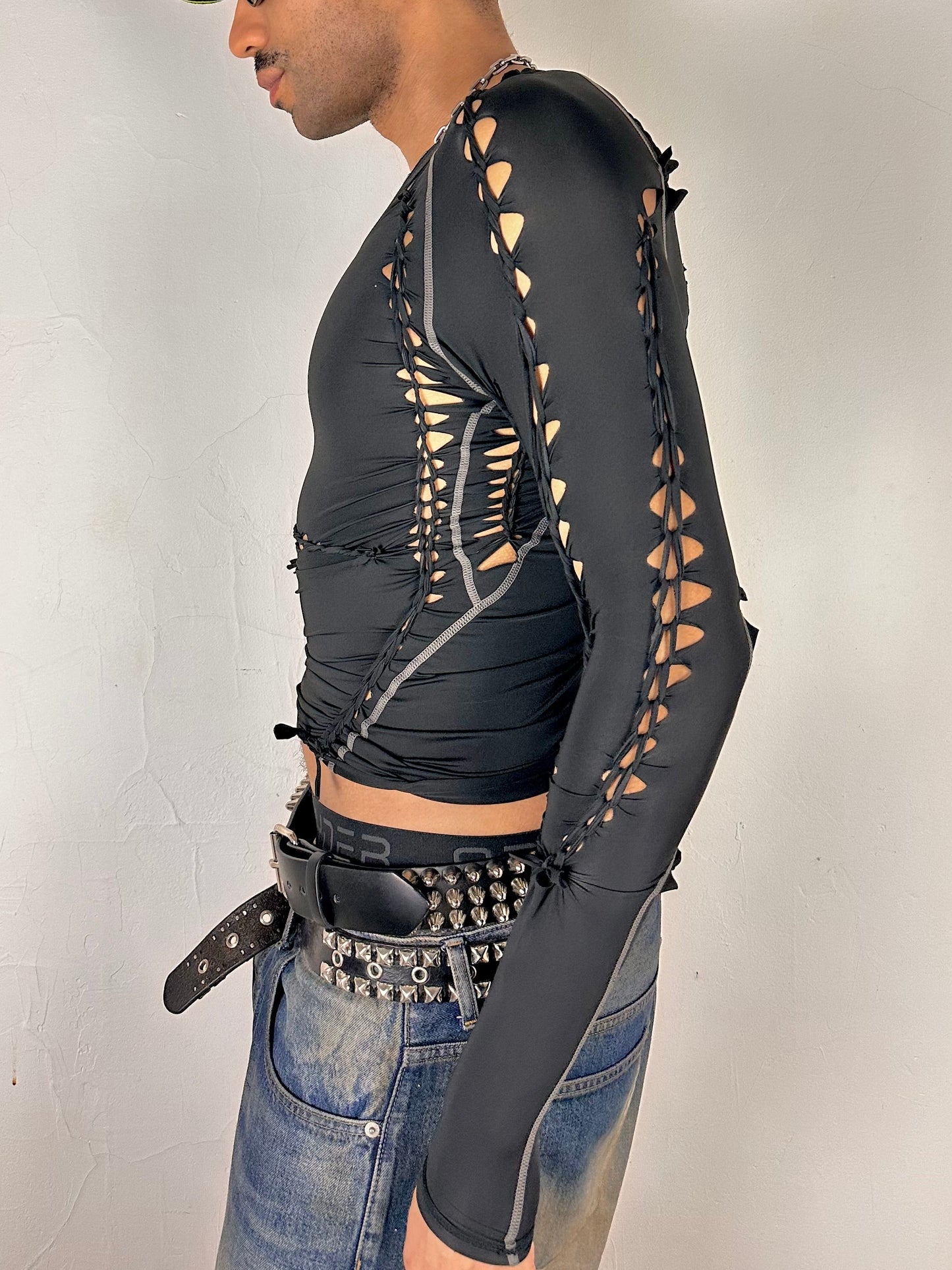 Left side of of ASTROBOI* 'Mystique' black braided twist compression top with cut-out details. Handmade in NYC using breathable, moisture-wicking stretch fabric.