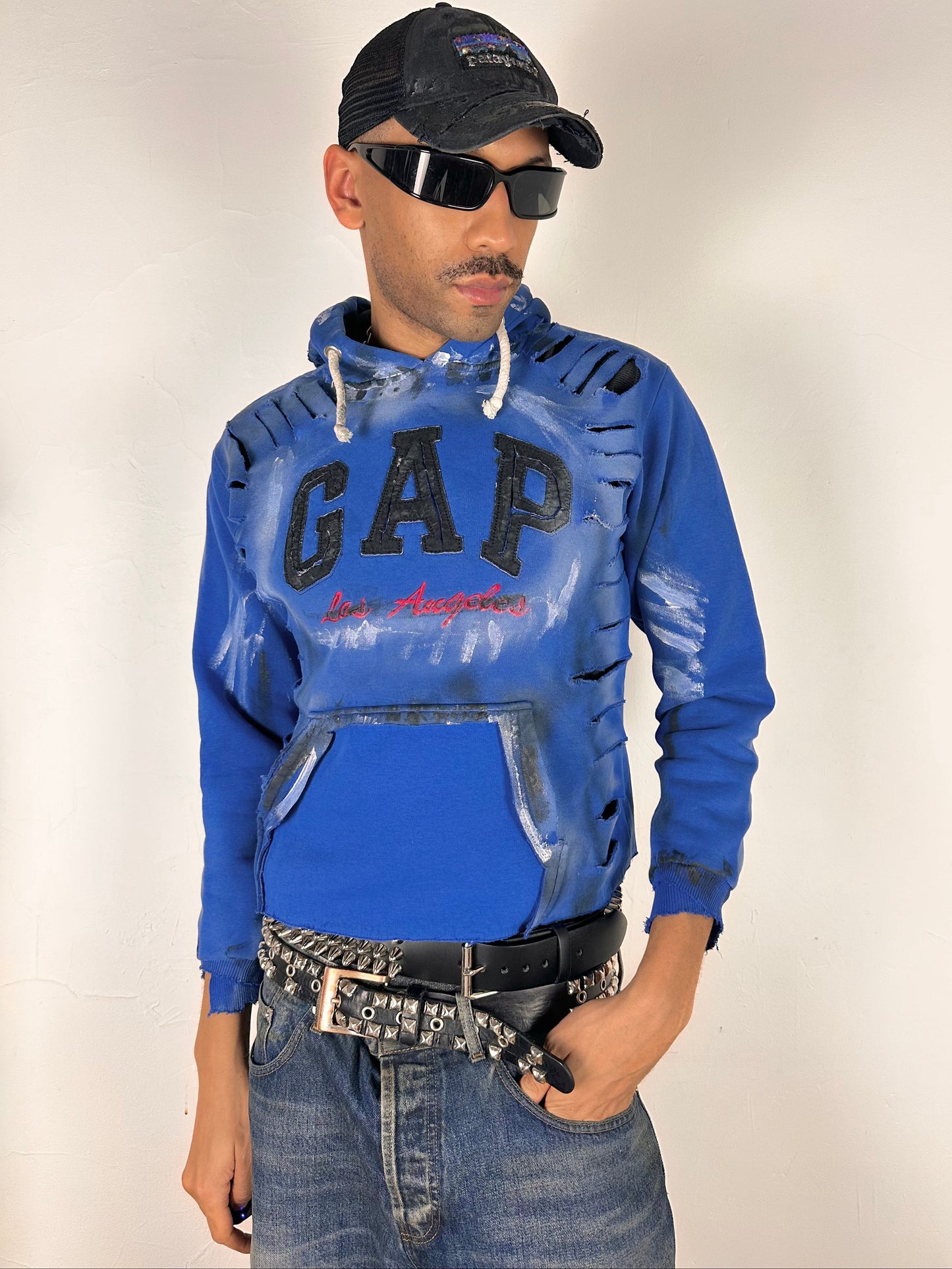 Styled image of ASTROBOI* x Gap blue distressed hoodie with airbrushed logo, ripped detailing, raw hem and rope drawcords, size Large loose fit.