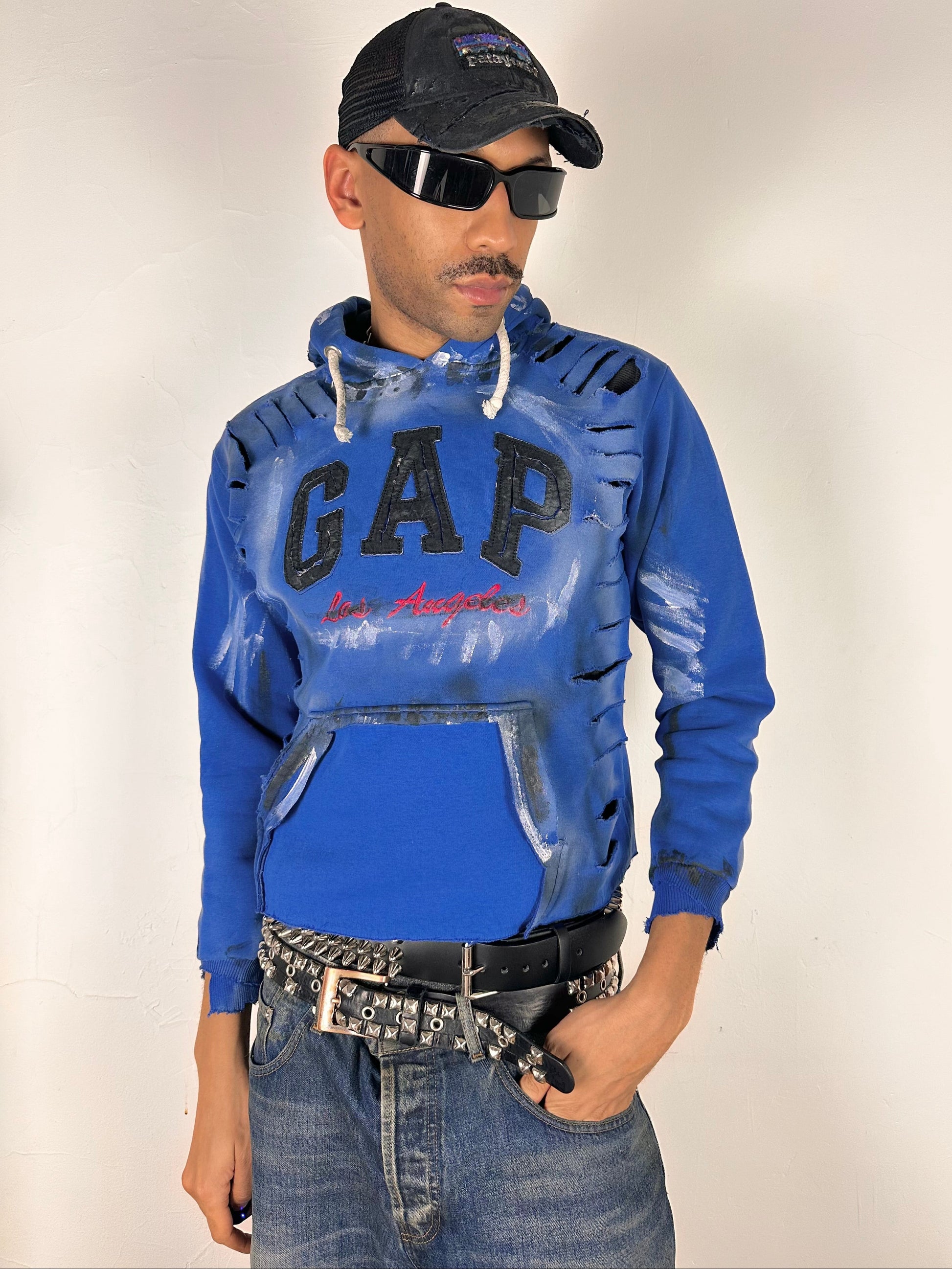 Styled image of ASTROBOI* x Gap blue distressed hoodie with airbrushed logo, ripped detailing, raw hem and rope drawcords, size Large loose fit.