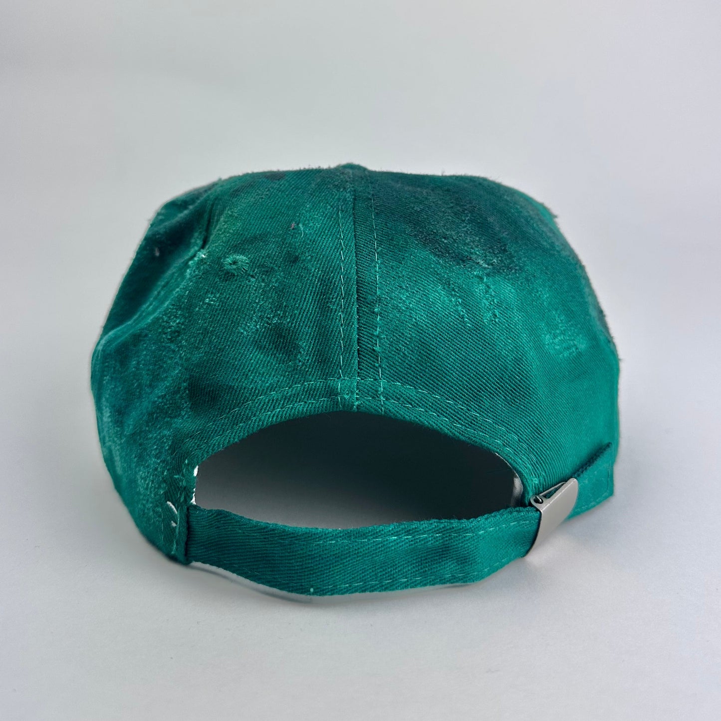 Back side of ASTROBOI* Smith NYC green distressed hat with clear rhinestone logo, custom paint treatment and blue black resin textured visor.