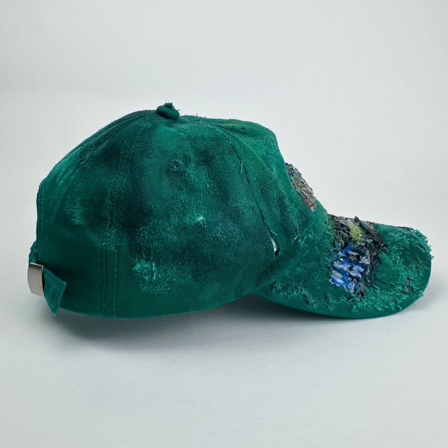 Right side of ASTROBOI* Smith NYC green distressed hat with clear rhinestone logo, custom paint treatment and blue black resin textured visor.