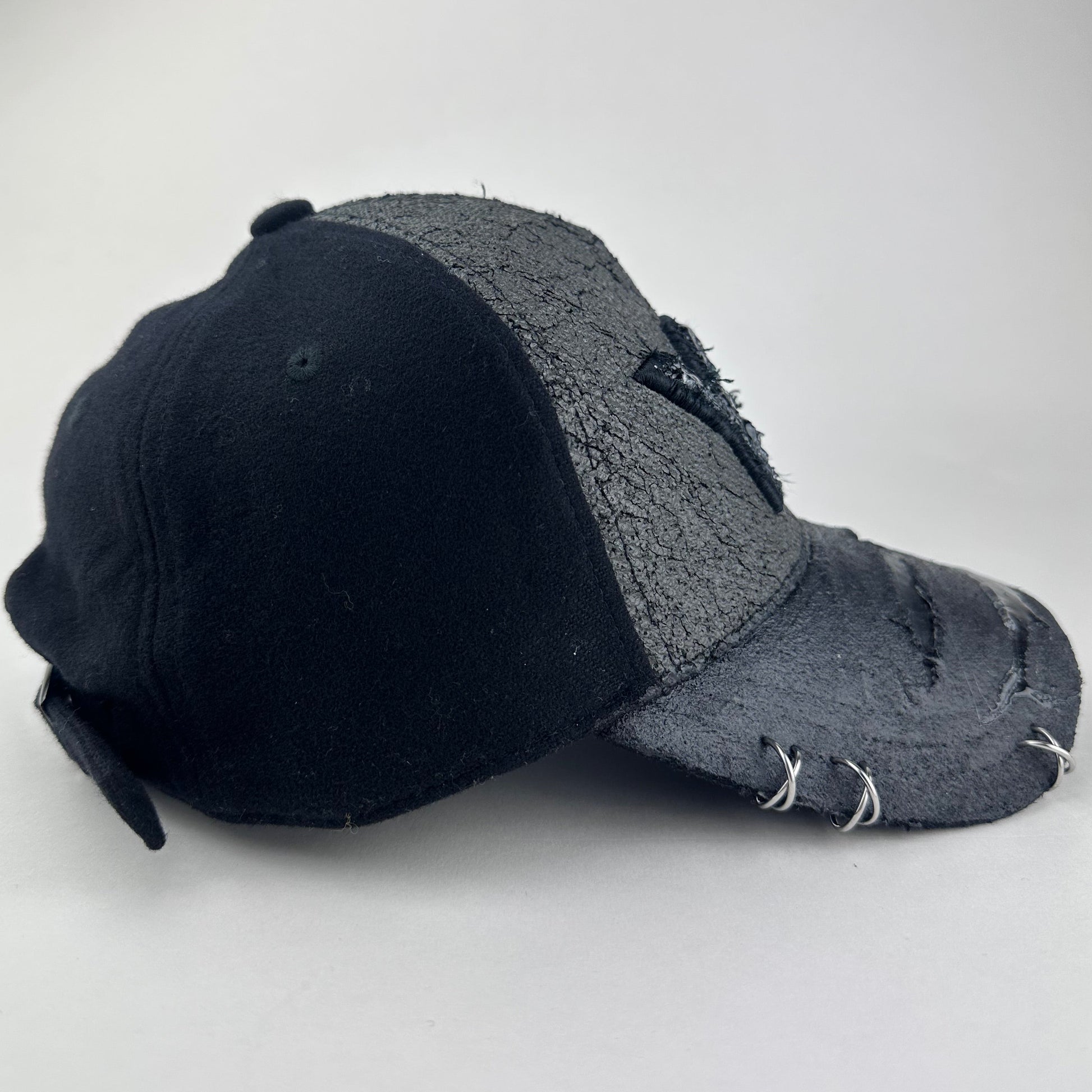 Right side of ASTROBOI* x Y-3 black distressed baseball cap with stainless steel piercings, cracked chrome effect, painted flannel, and center Y-3 logo.