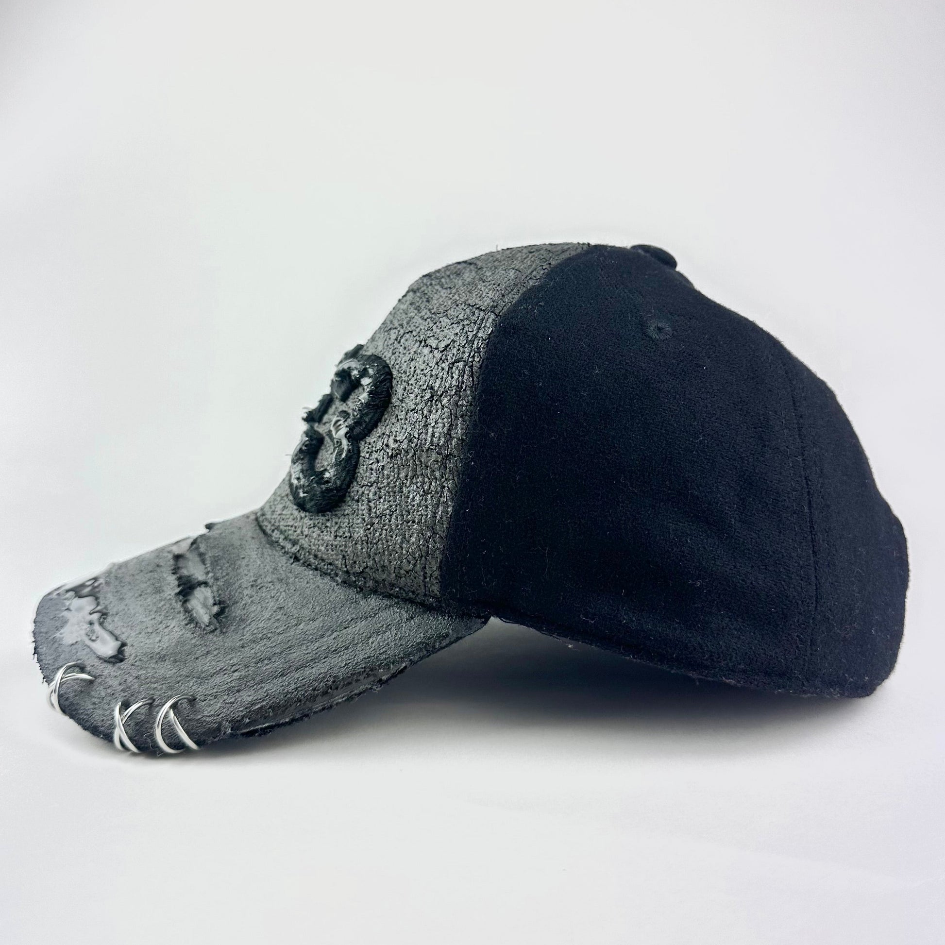 Left side of ASTROBOI* x Y-3 black distressed baseball cap with stainless steel piercings, cracked chrome effect, painted flannel, and center Y-3 logo.