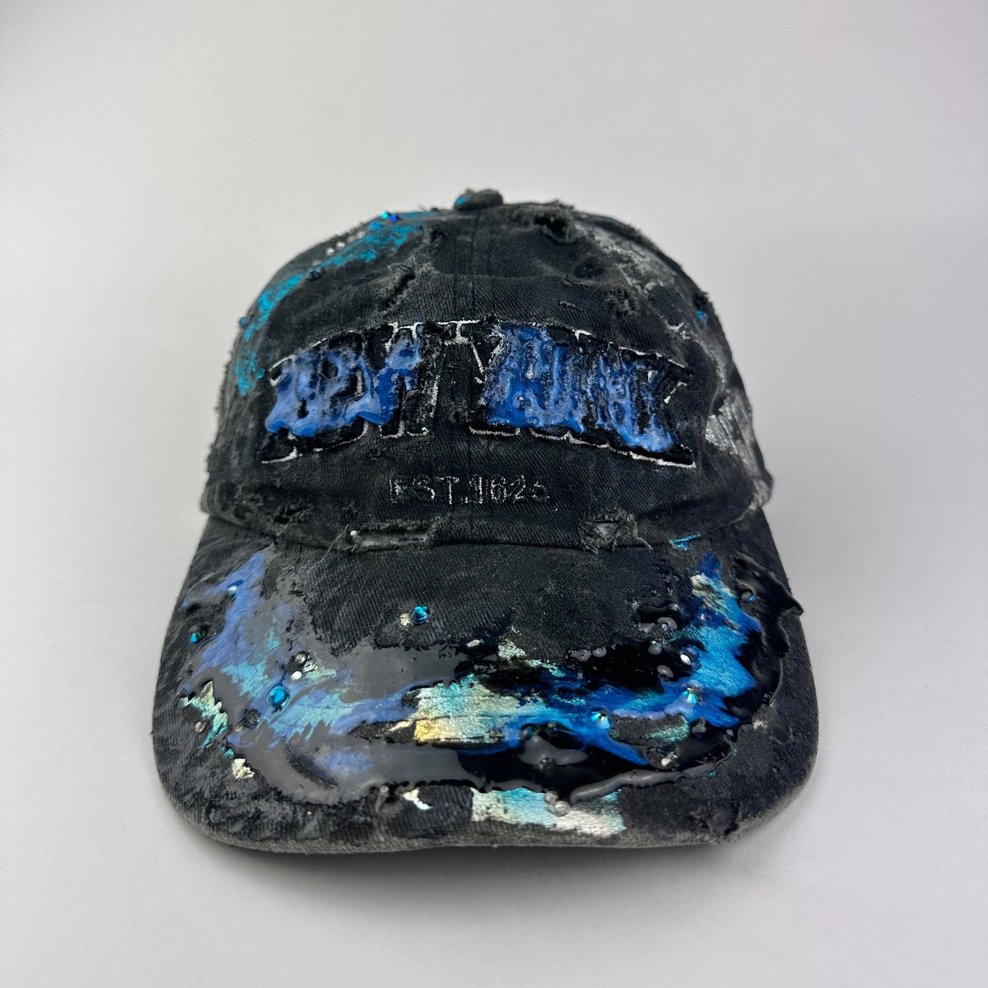 Alternative front view of ASTROBOI* Plavala black iridescent hat with rhinestone NYC logos, metallic paint and black clear resin creating a hazy milky way effect.